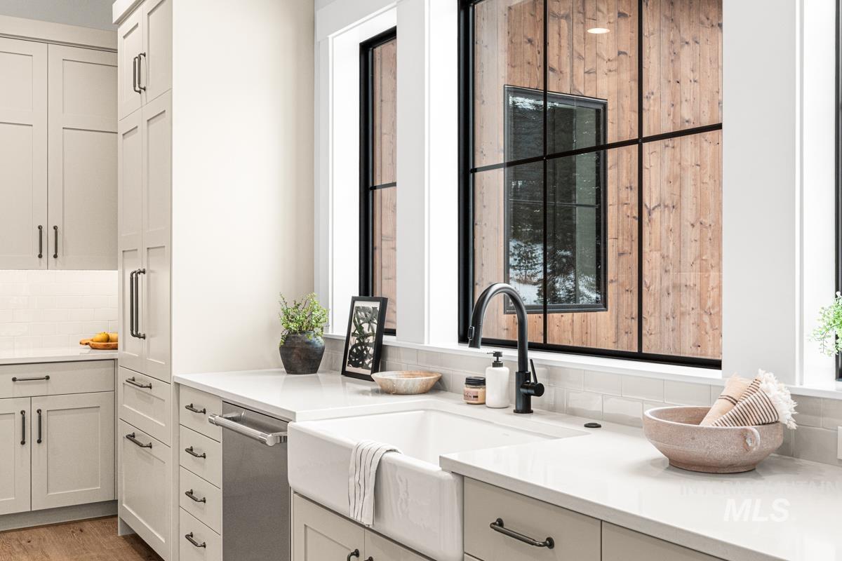 Kitchen featuring decorative backsplash, stainless steel dishwasher, white cabinetry, and light stone counters