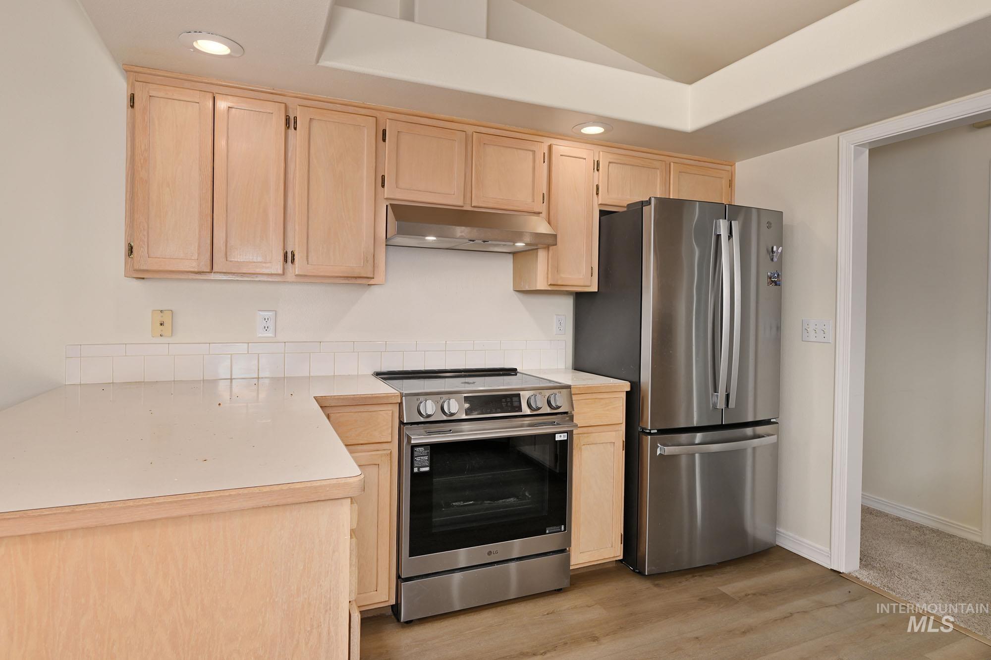 Kitchen featuring light-toned cabinetry, white countertops, and a white tile backsplash