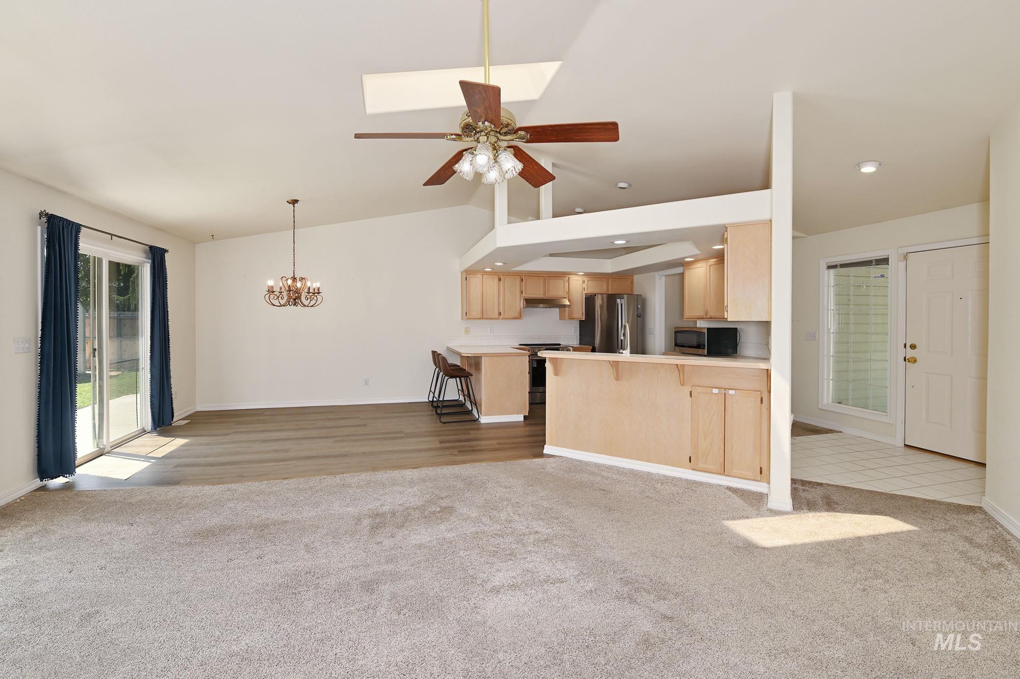 Open-concept living area featuring vaulted ceilings, a skylight, and a ceiling fan