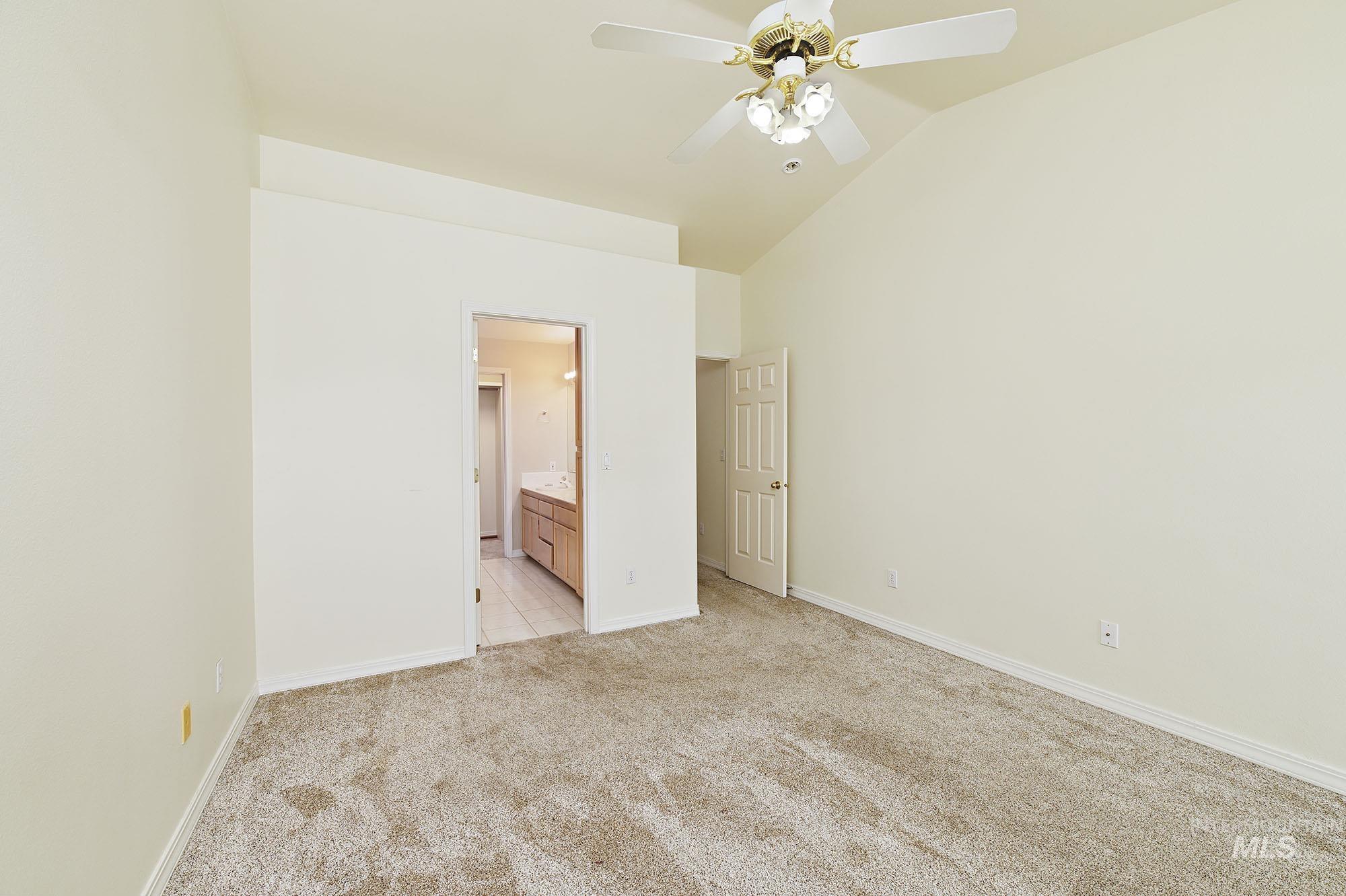 Carpeted bedroom with vaulted ceilings and a ceiling fan