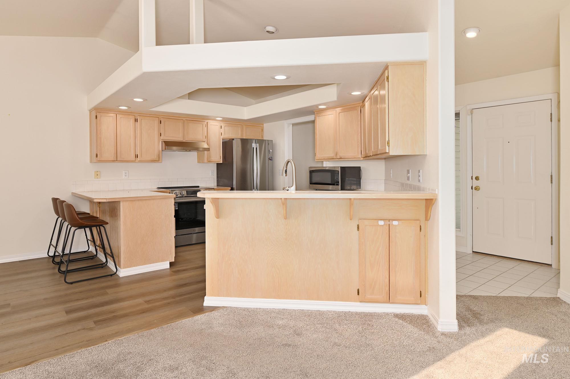 Kitchen featuring light wood-finish cabinetry, white countertops, stainless steel appliances, and recessed lighting