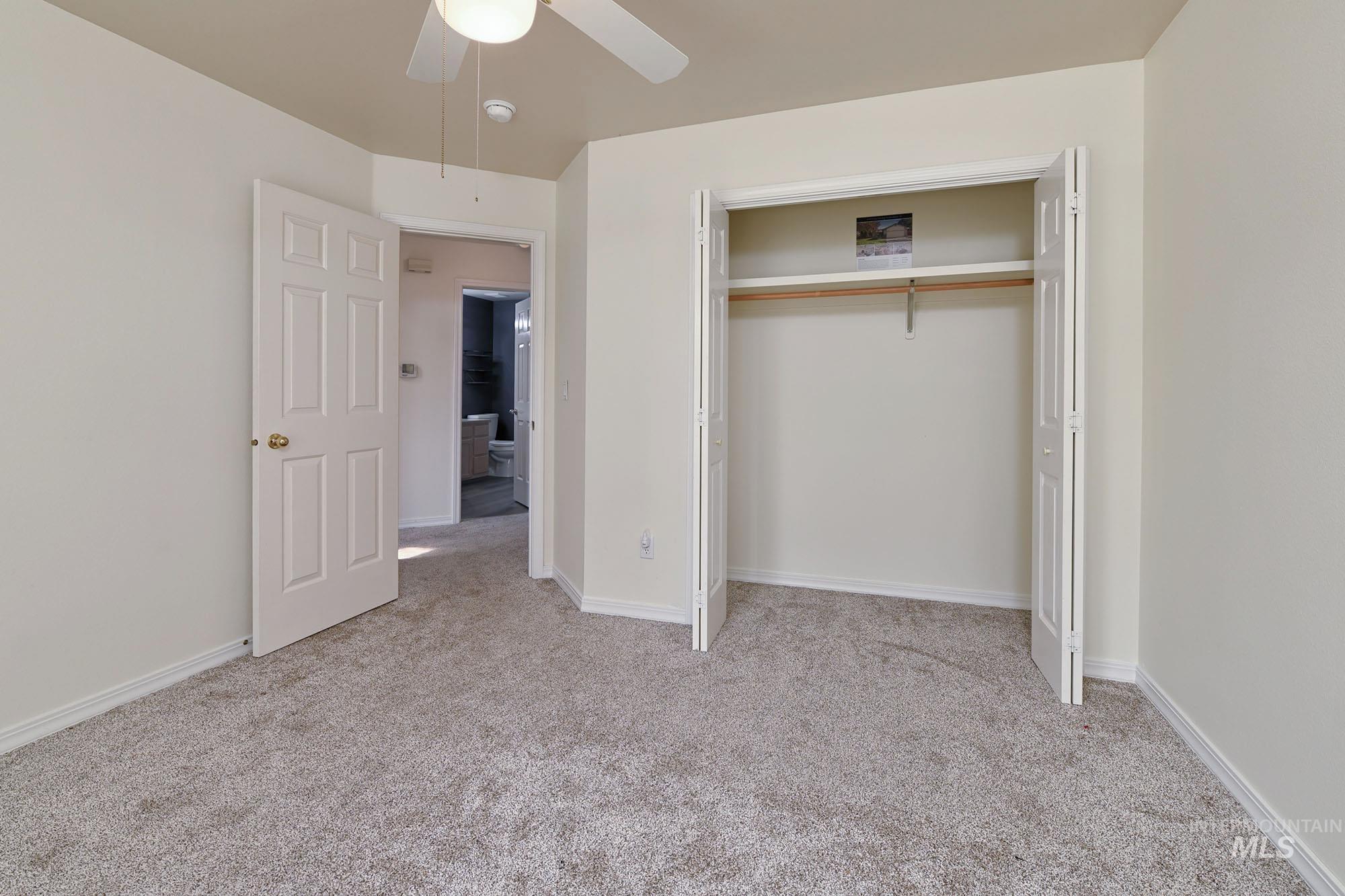 Carpeted room featuring a ceiling fan, white paneled doors, and a bi-fold closet