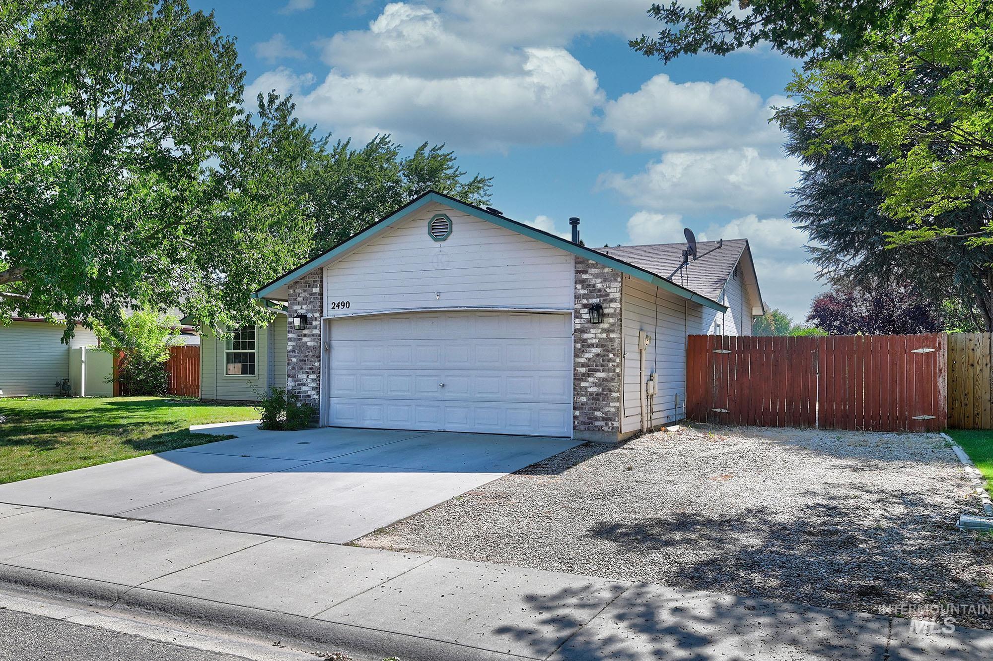 Single-story home featuring a two-car garage, brick facade accents, and a light-colored exterior