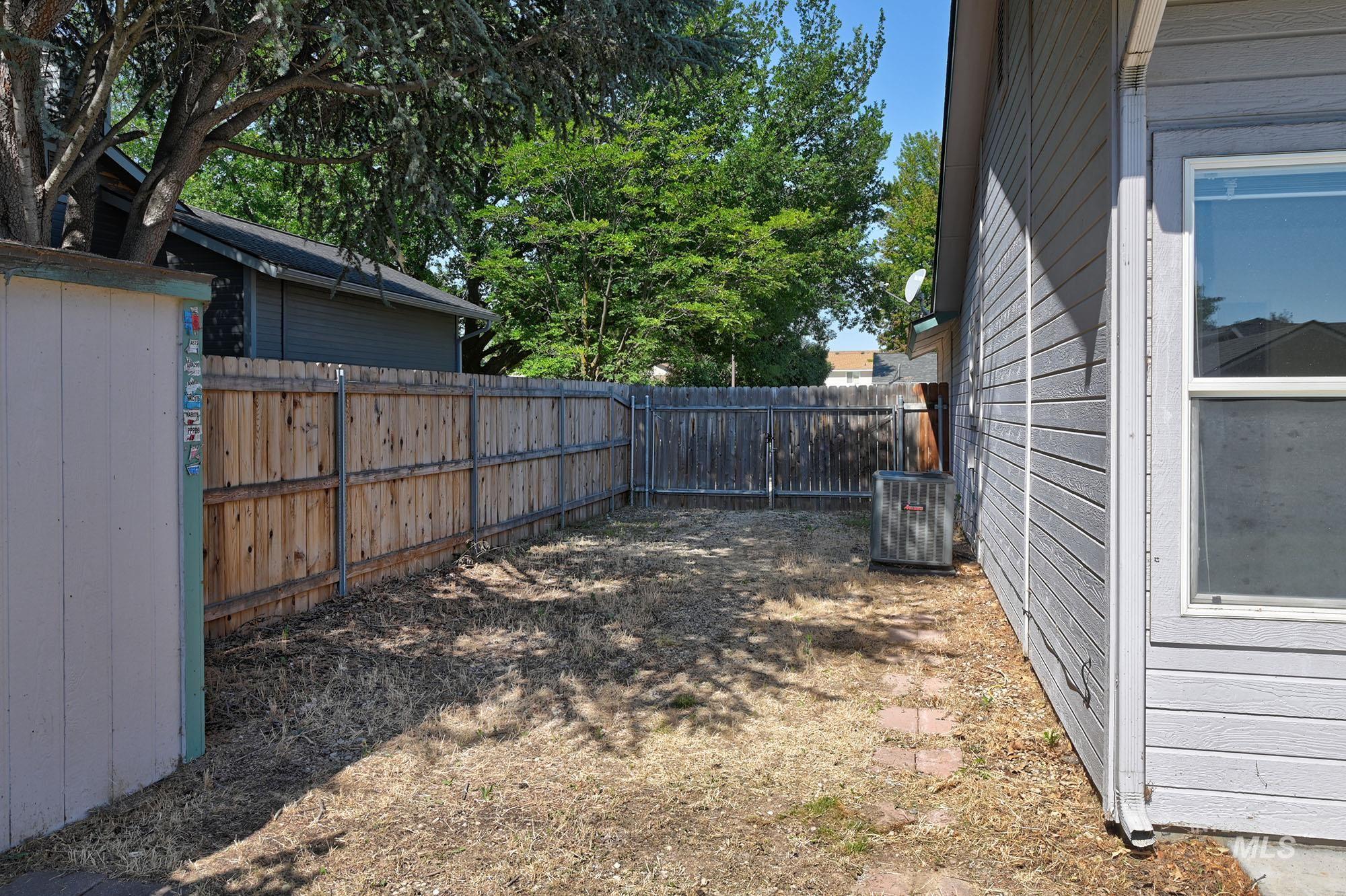 Fenced backyard featuring wood paneling along the property line and brick pathing