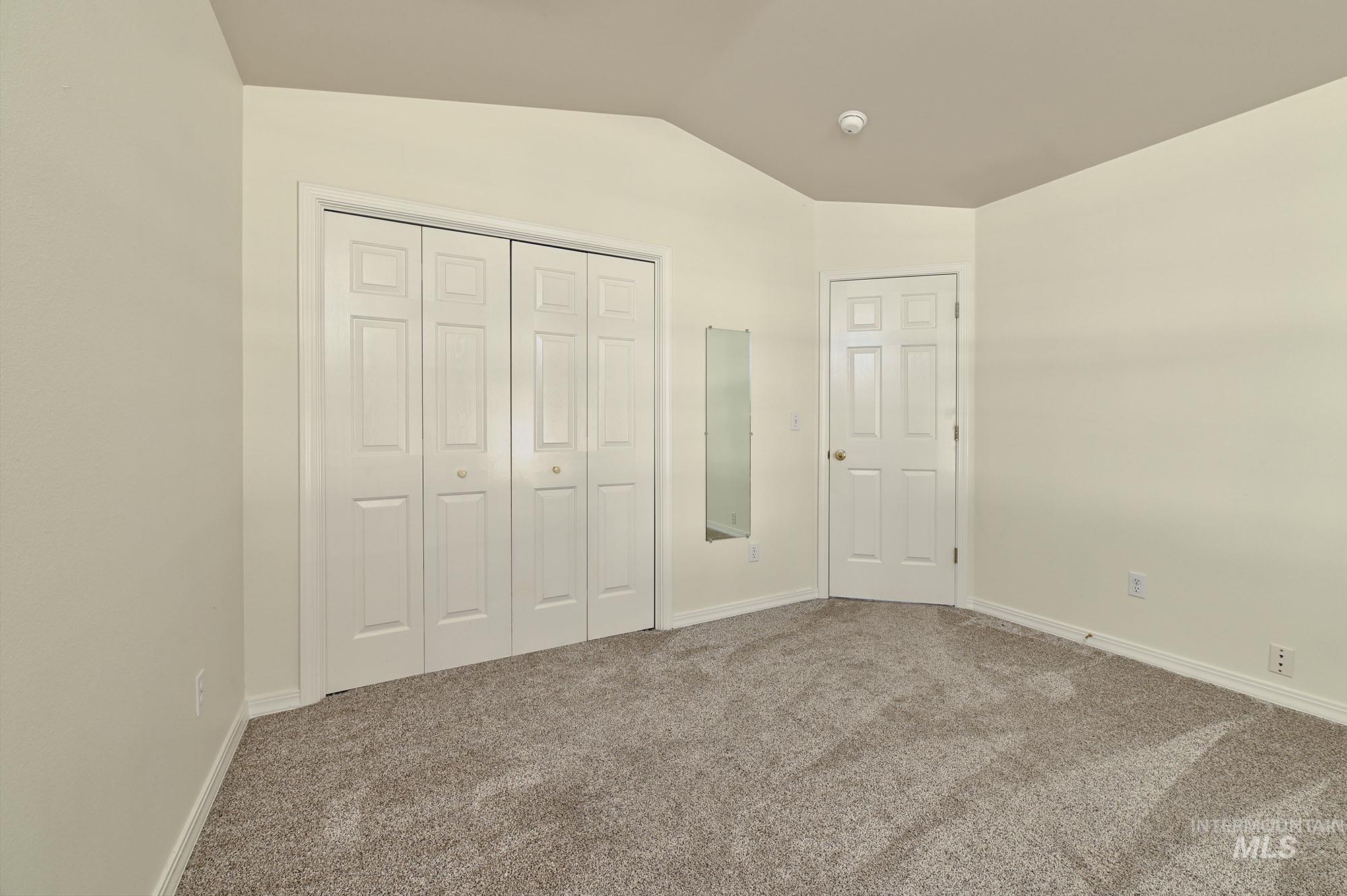Room featuring neutral-toned walls, vaulted ceiling, and gray carpeting