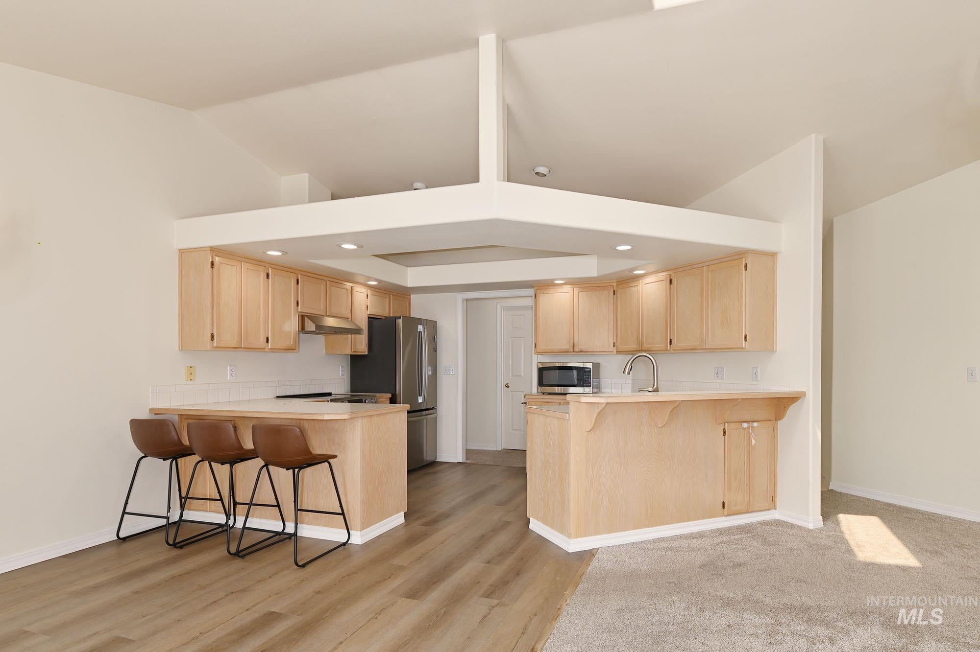 Kitchen featuring light wood cabinetry, white subway tile backsplash, and stainless steel appliances
