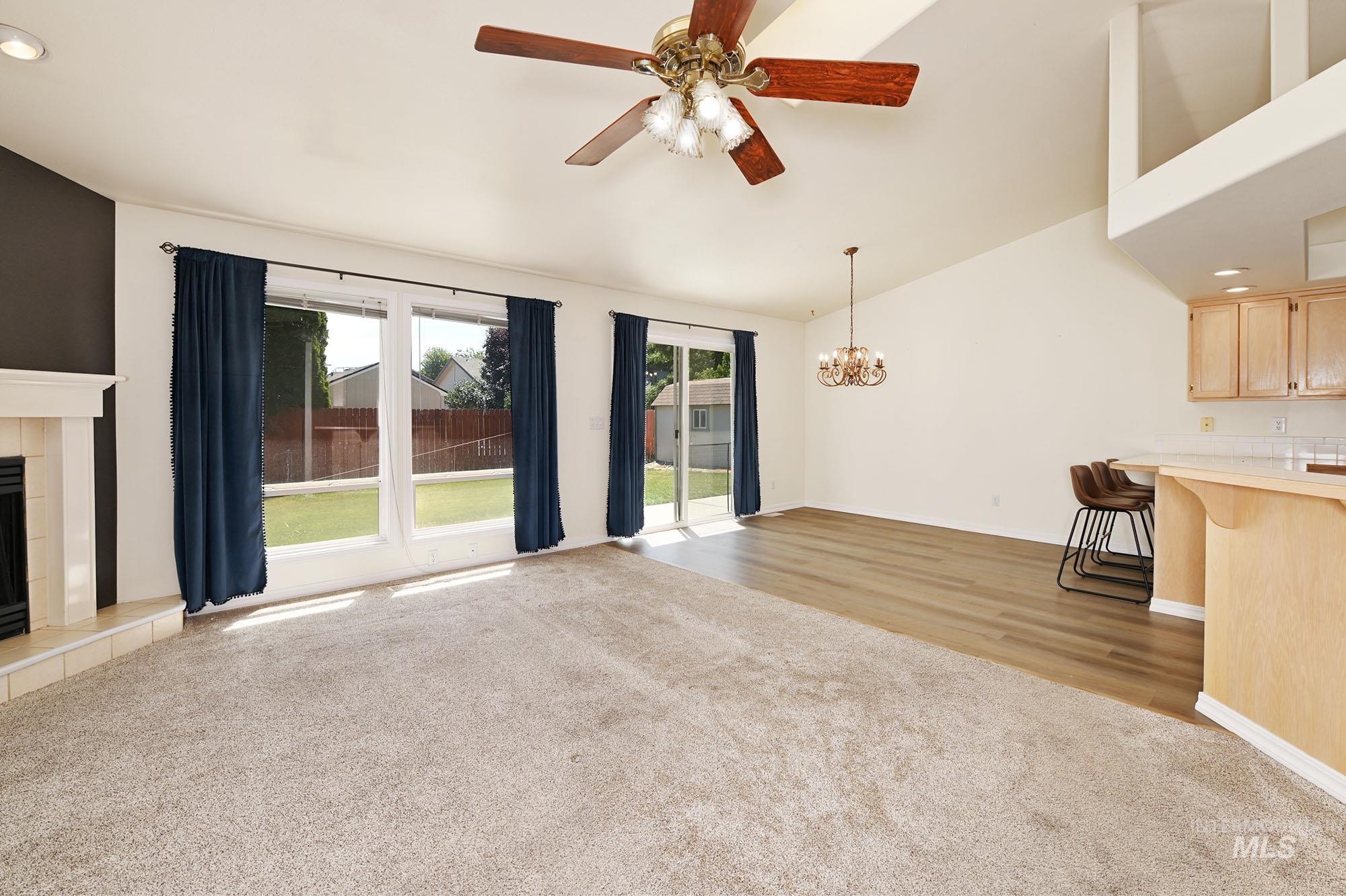 Vaulted ceilings complement the living space, featuring a ceiling fan with integrated lighting
