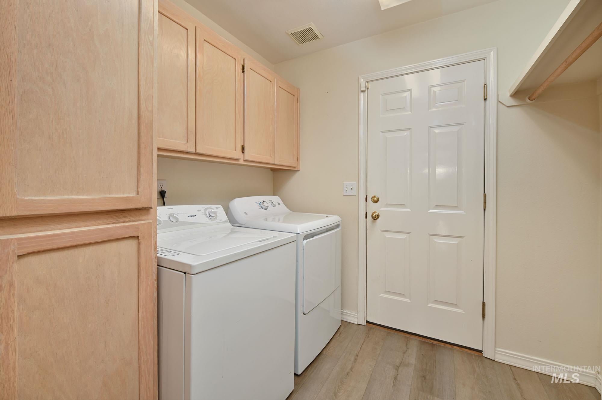 Laundry area featuring overhead cabinetry, built-in storage, wood-finish flooring, and a six-panel door
