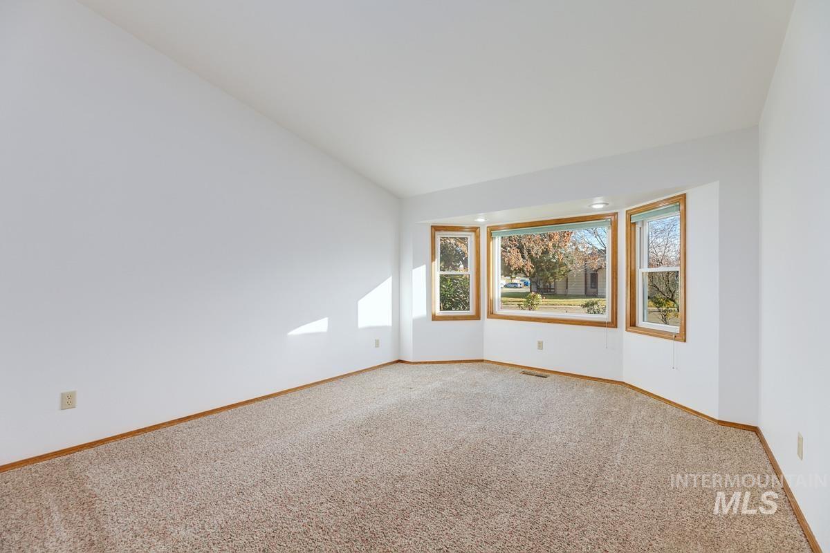 Carpeted spare room with vaulted ceiling and baseboards