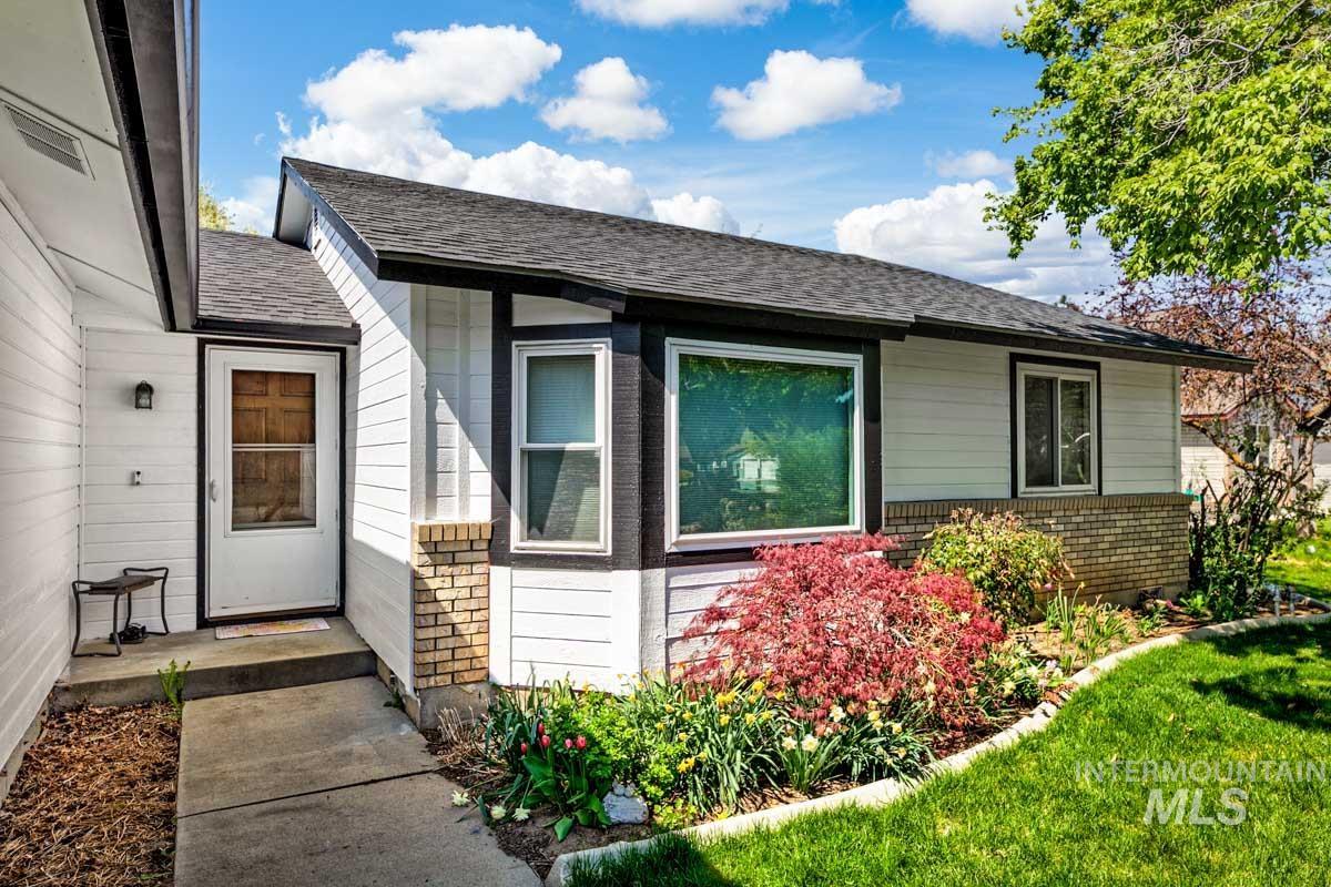 Doorway to property with brick siding, roof with shingles, and a lawn