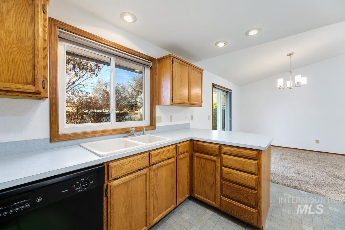 Kitchen with light countertops, dishwasher, light carpet, a peninsula, and vaulted ceiling