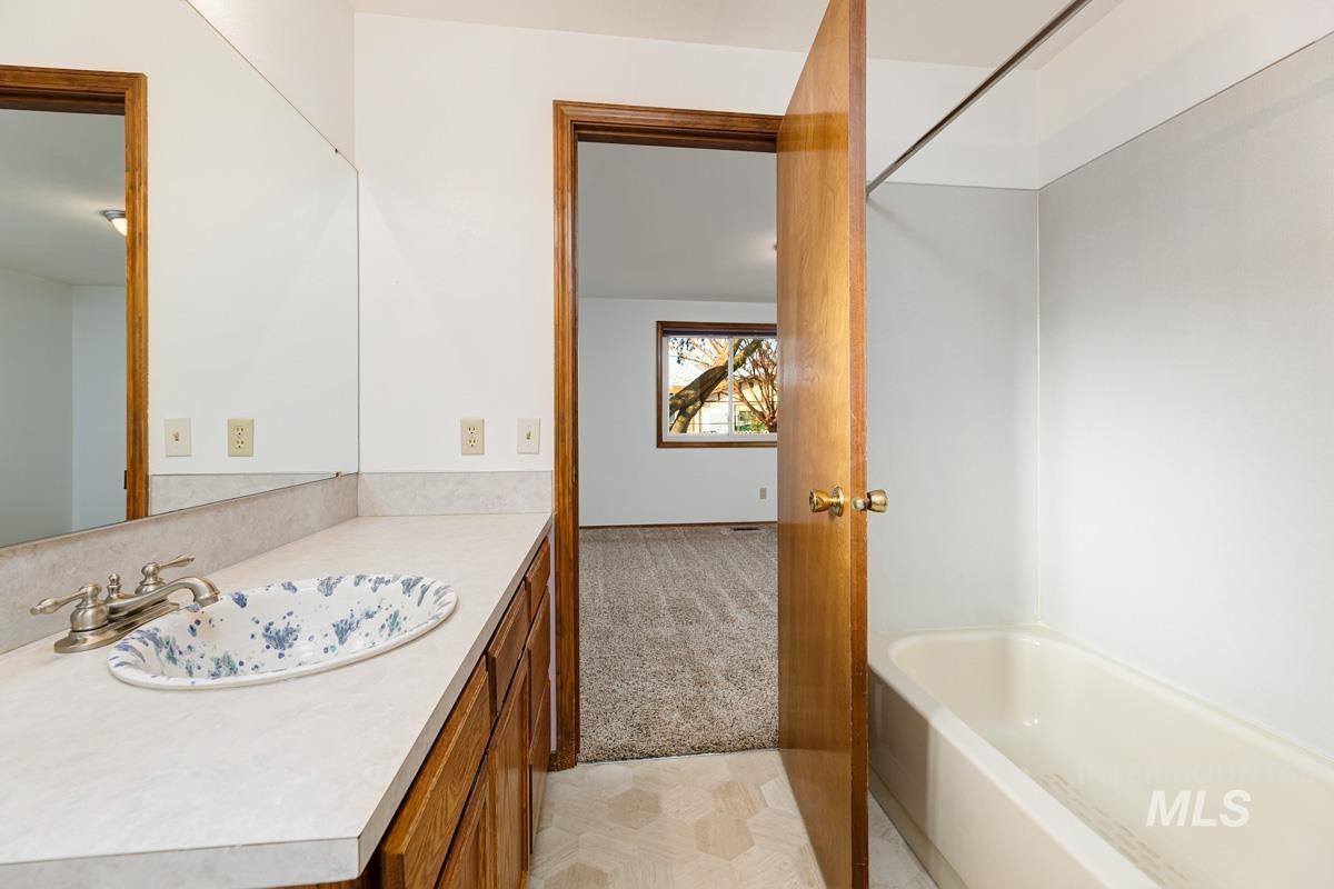 Bathroom with light carpet, vanity, and a tub