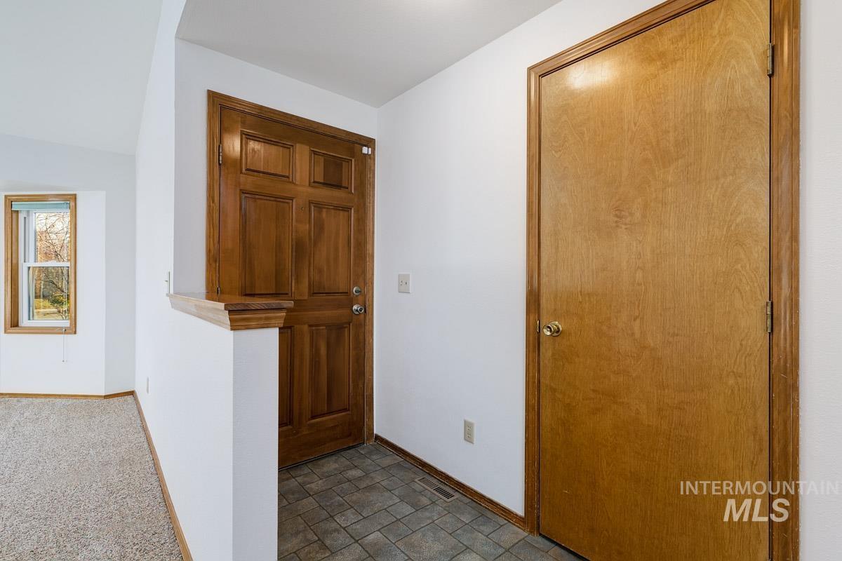 Hall with baseboards and dark colored carpet