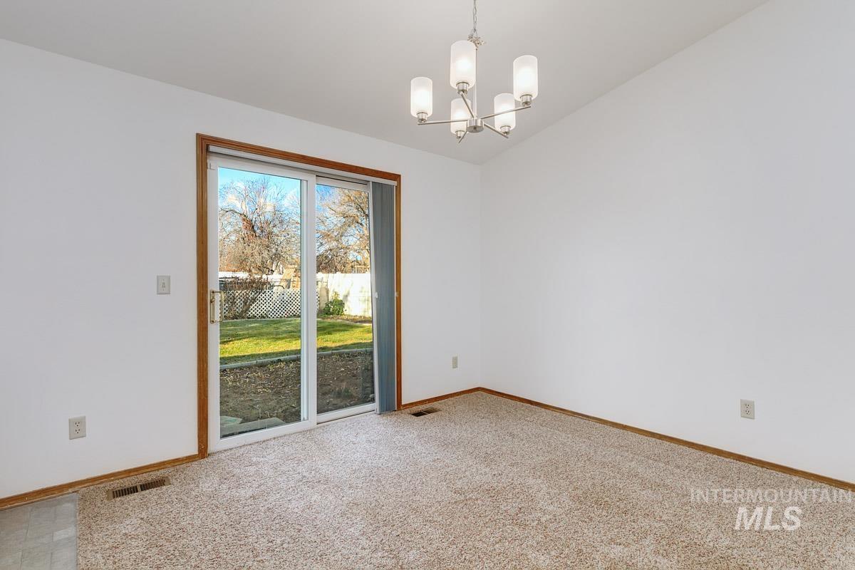 Spare room with light carpet and a chandelier