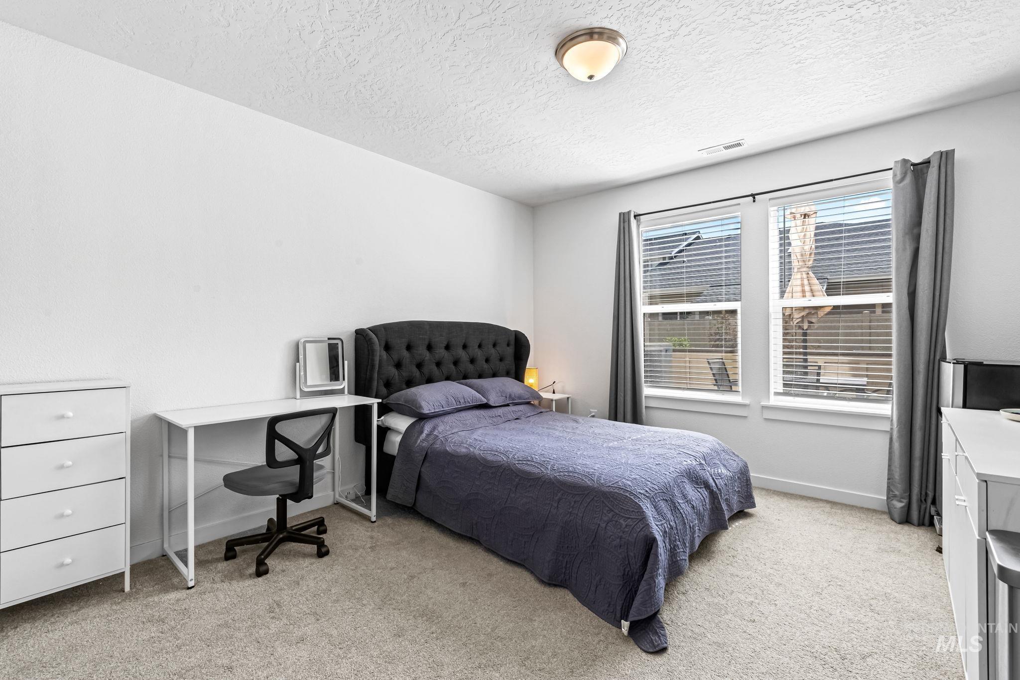Bedroom featuring light colored carpet and a textured ceiling