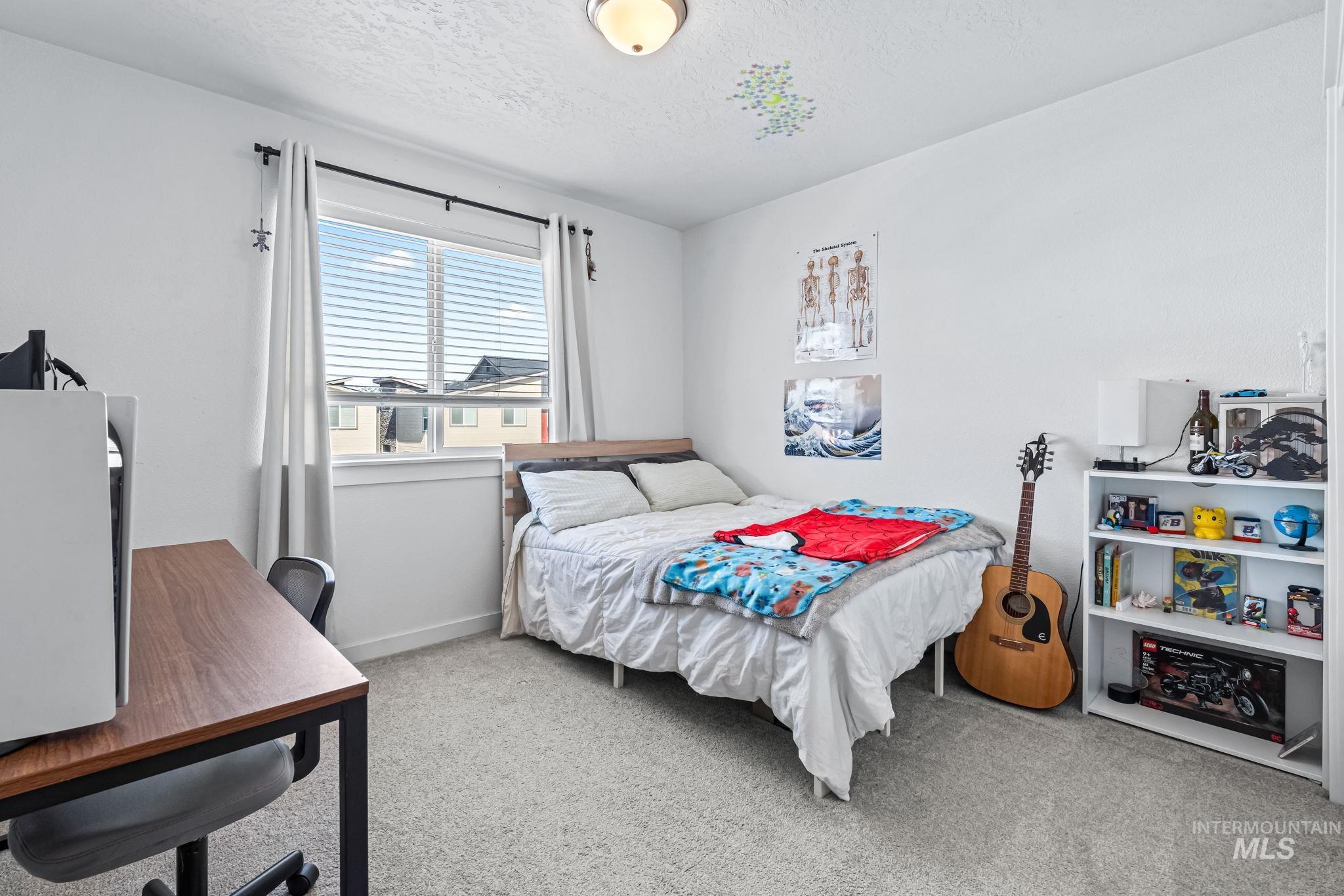 Carpeted bedroom featuring a textured ceiling and a desk