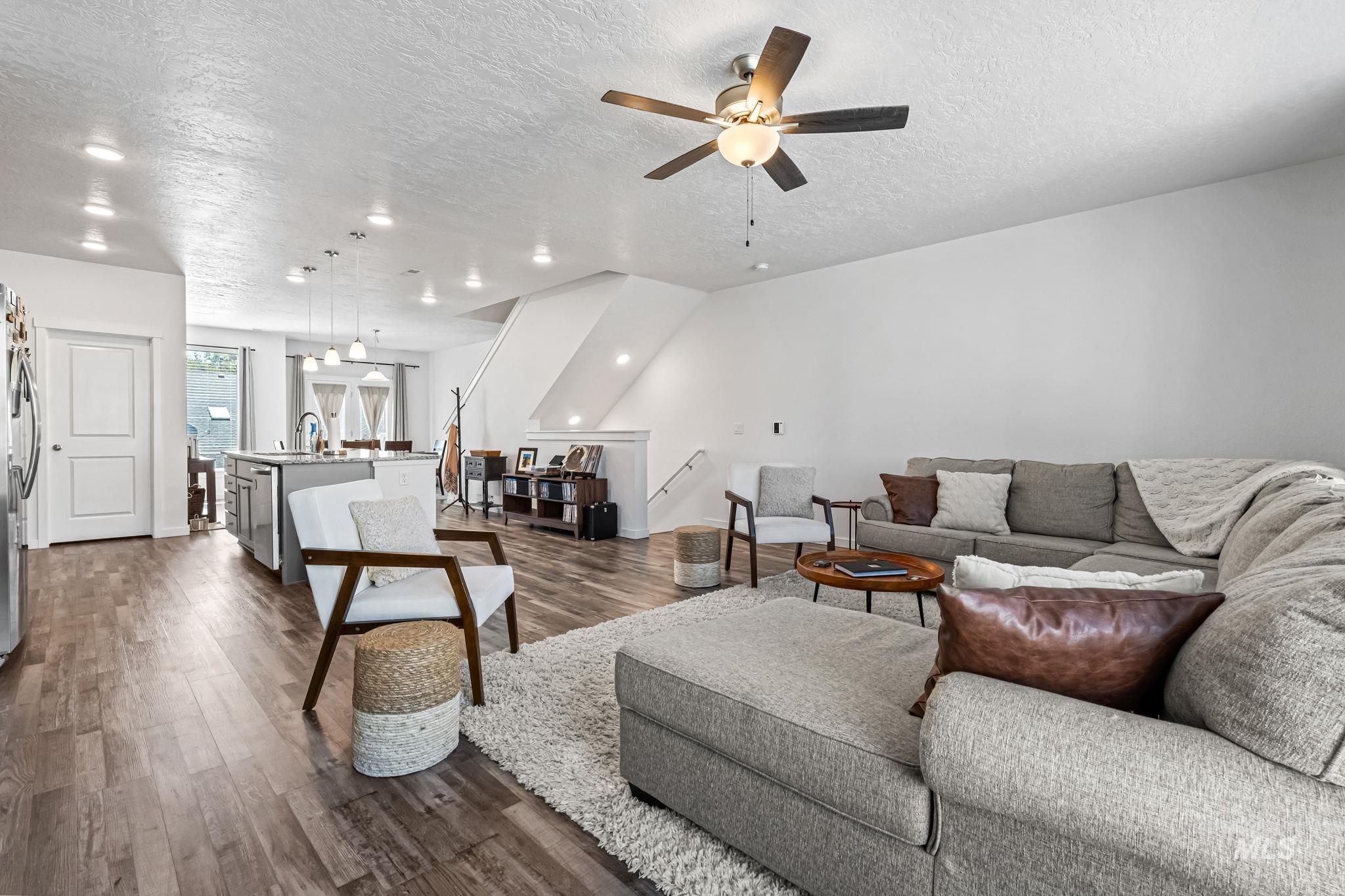 Living room featuring a textured ceiling, dark wood finished floors, and ceiling fan