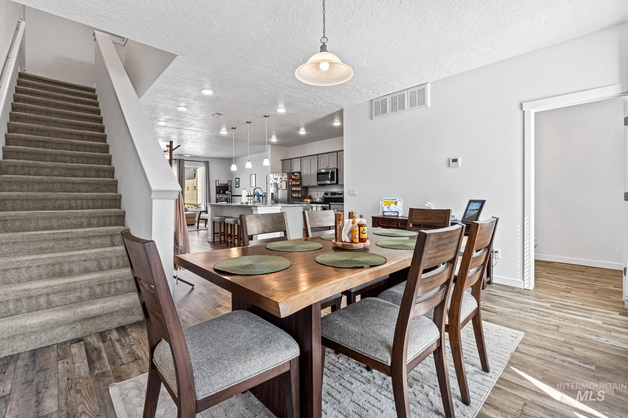 Dining area with stairway, a textured ceiling, light wood-type flooring, and recessed lighting