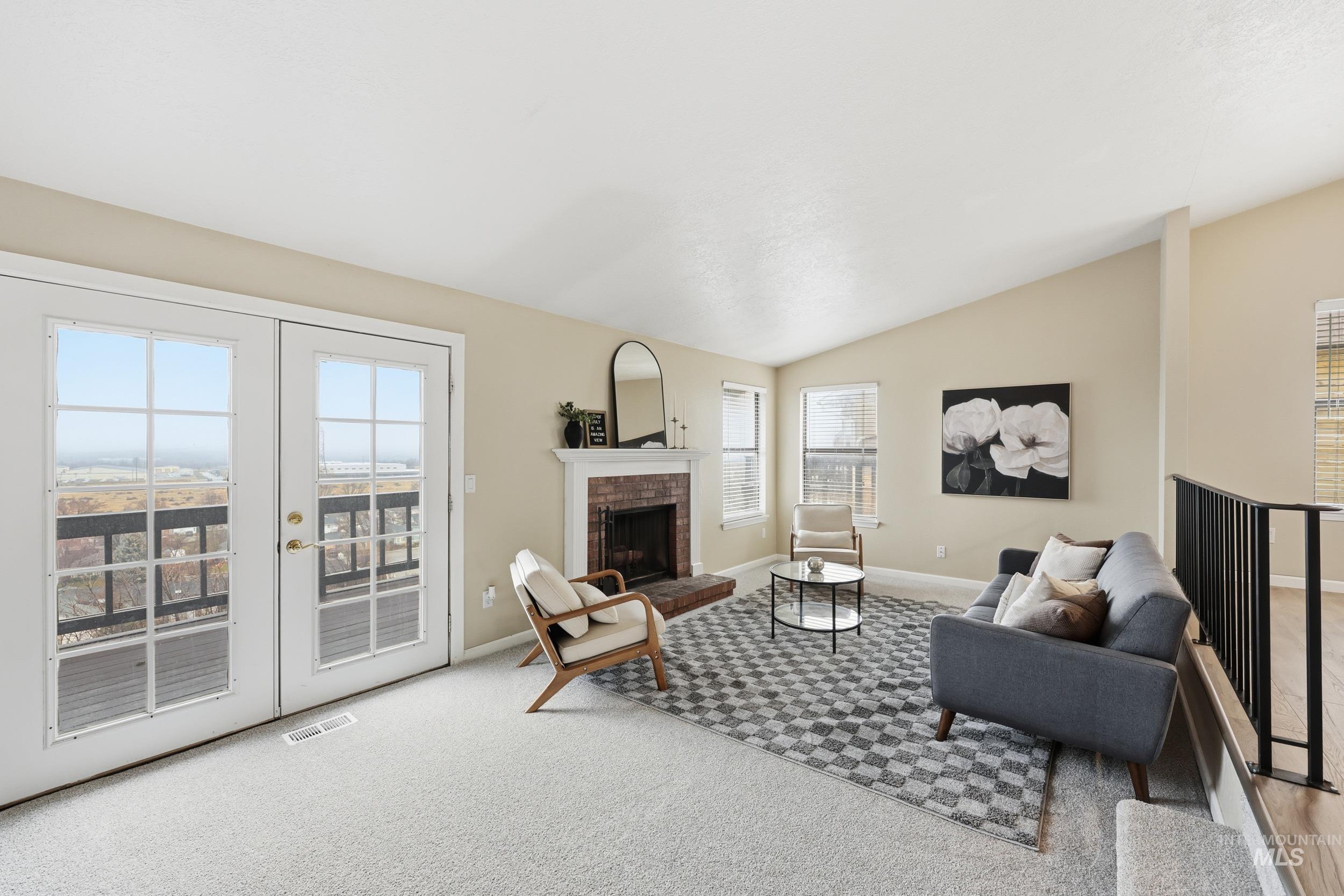 Living area featuring a fireplace, lofted ceiling, carpet floors, and french doors