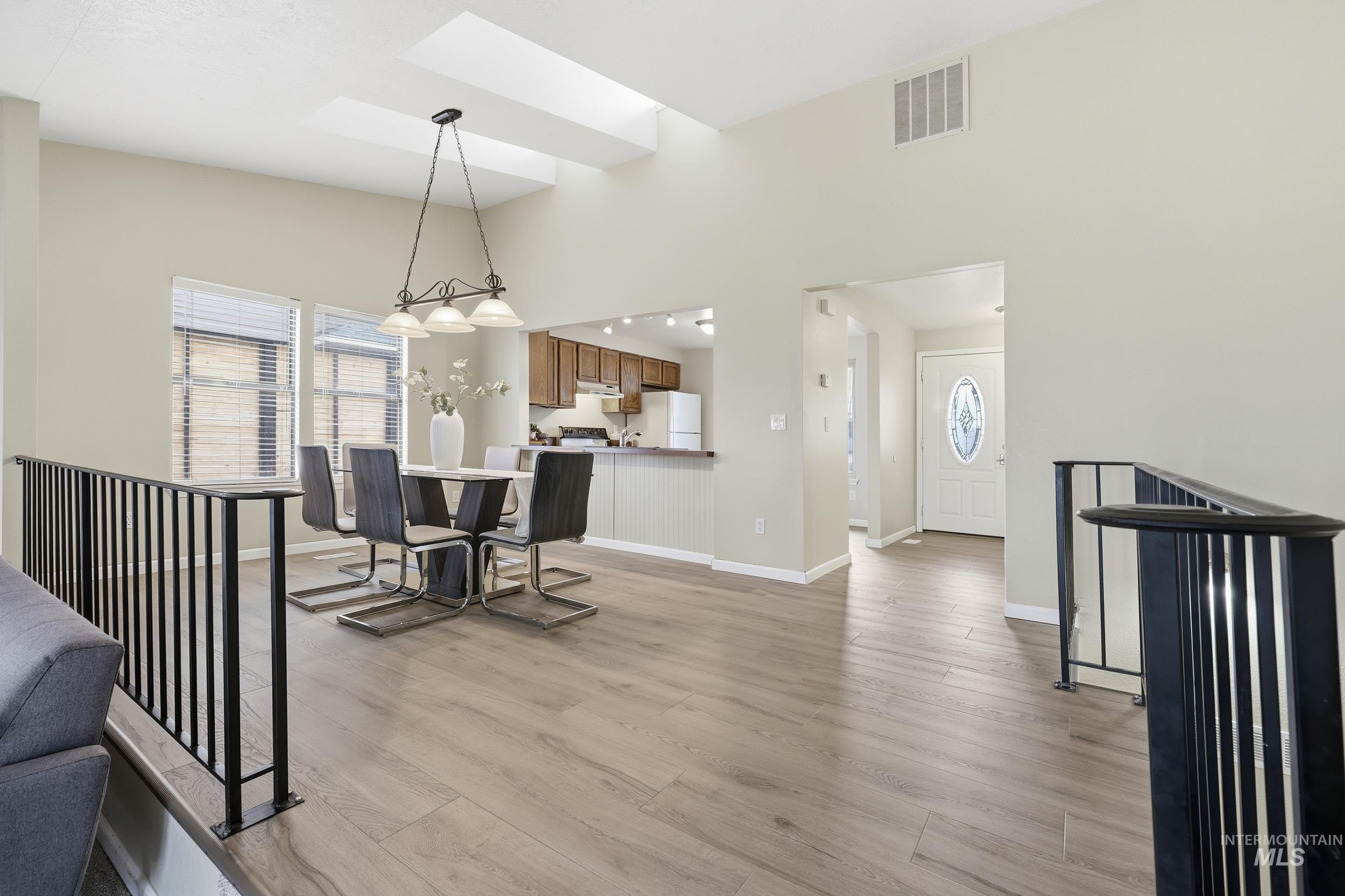 Dining room with light wood-style flooring and high vaulted ceiling