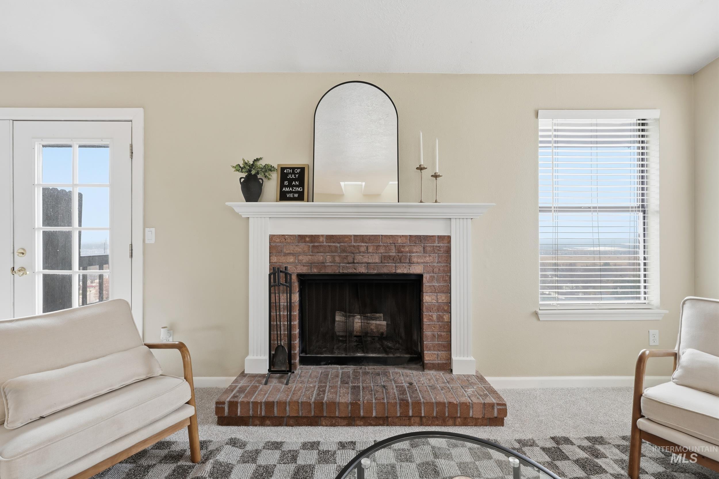 Carpeted living room with a brick fireplace and baseboards