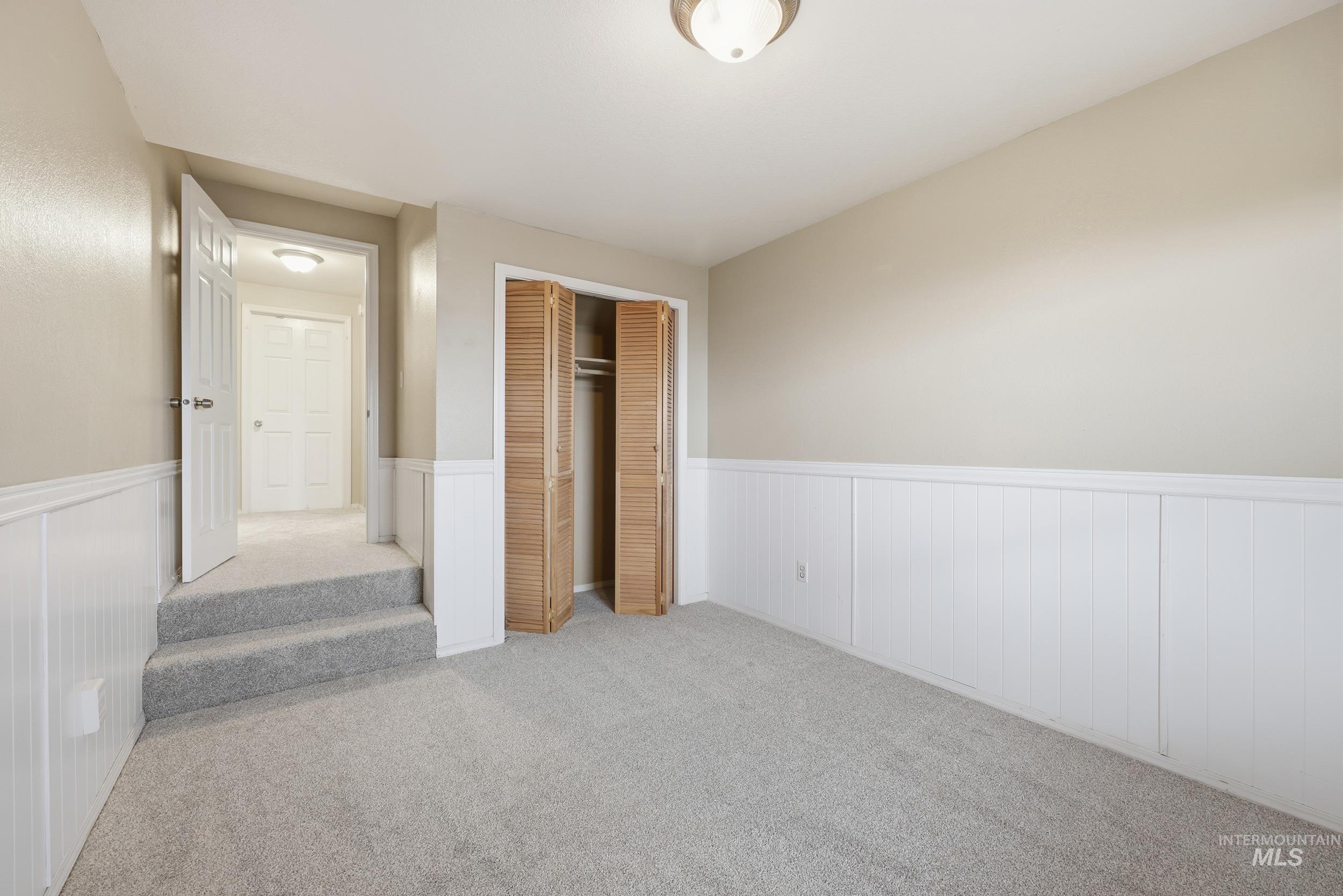 Unfurnished bedroom featuring a closet, carpet, and wainscoting
