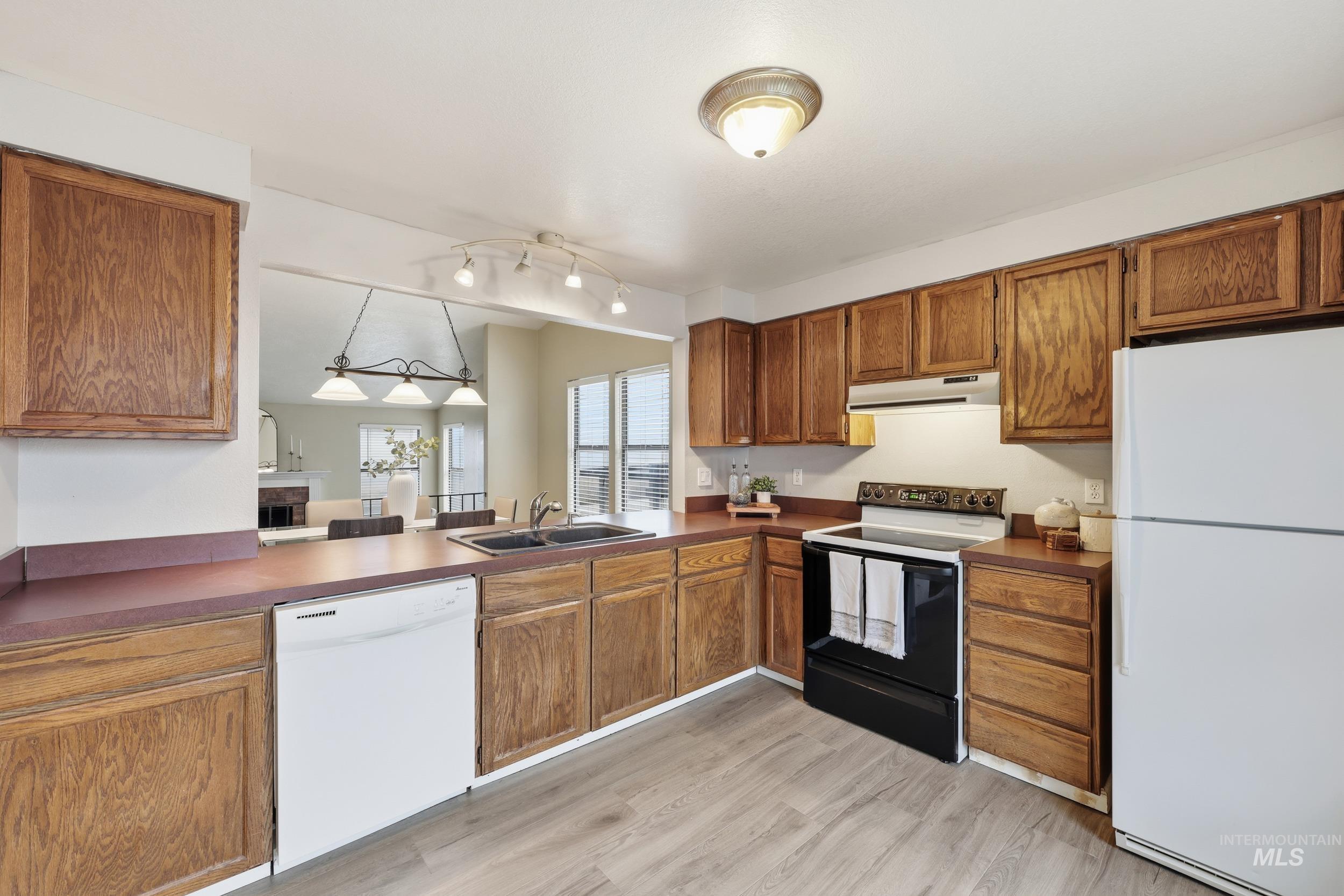 Kitchen featuring white appliances, brown cabinets, and dark countertops