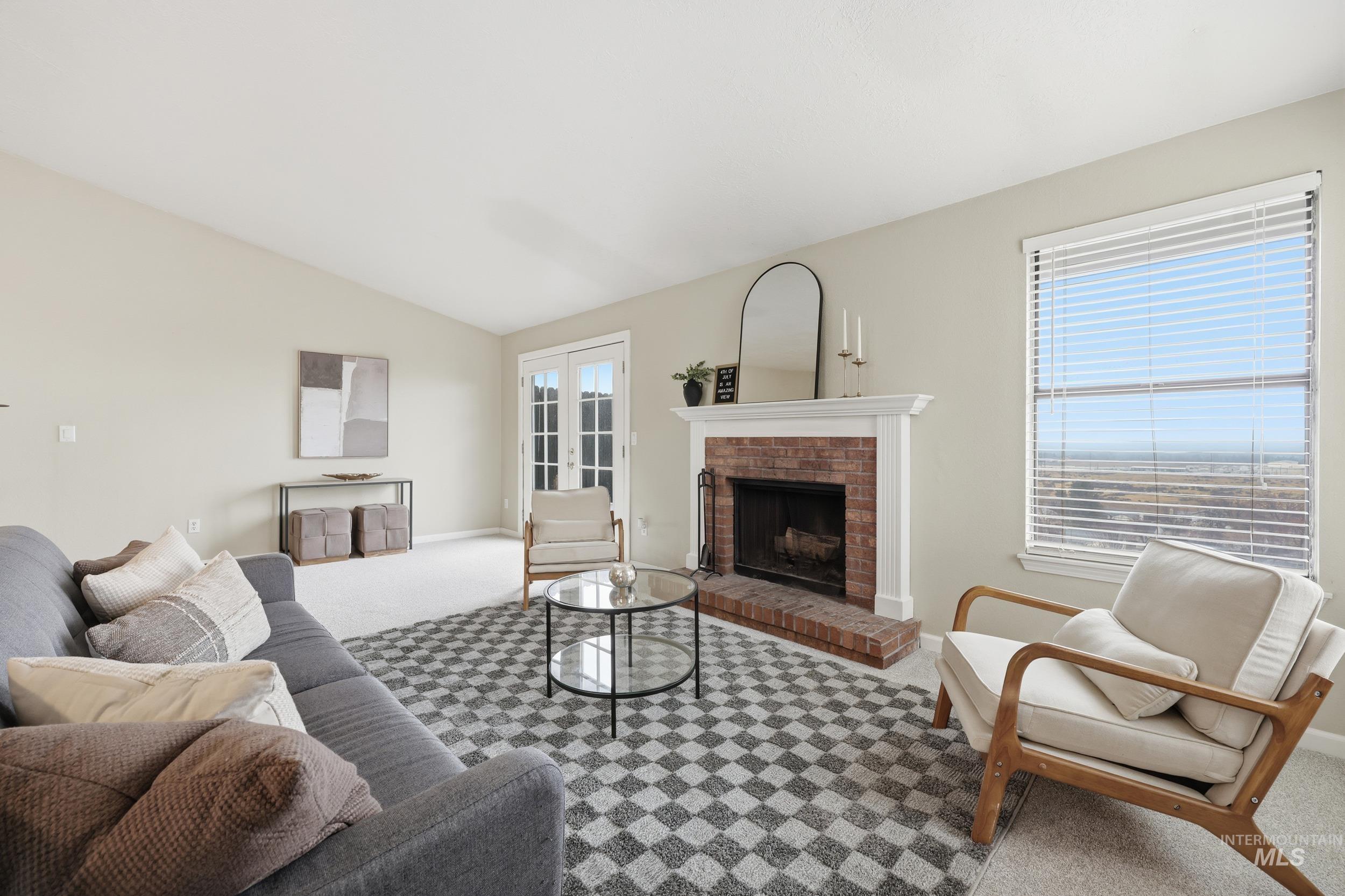 Carpeted living area with a brick fireplace and lofted ceiling