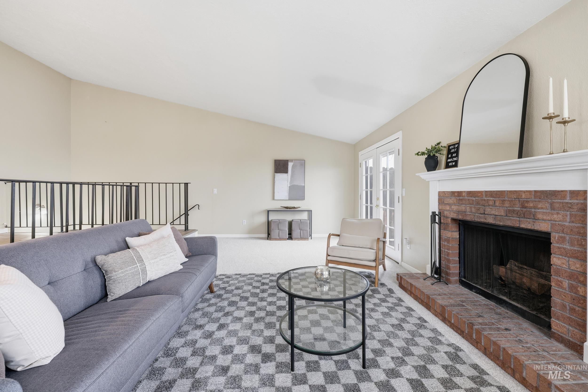Carpeted living area with lofted ceiling and a fireplace