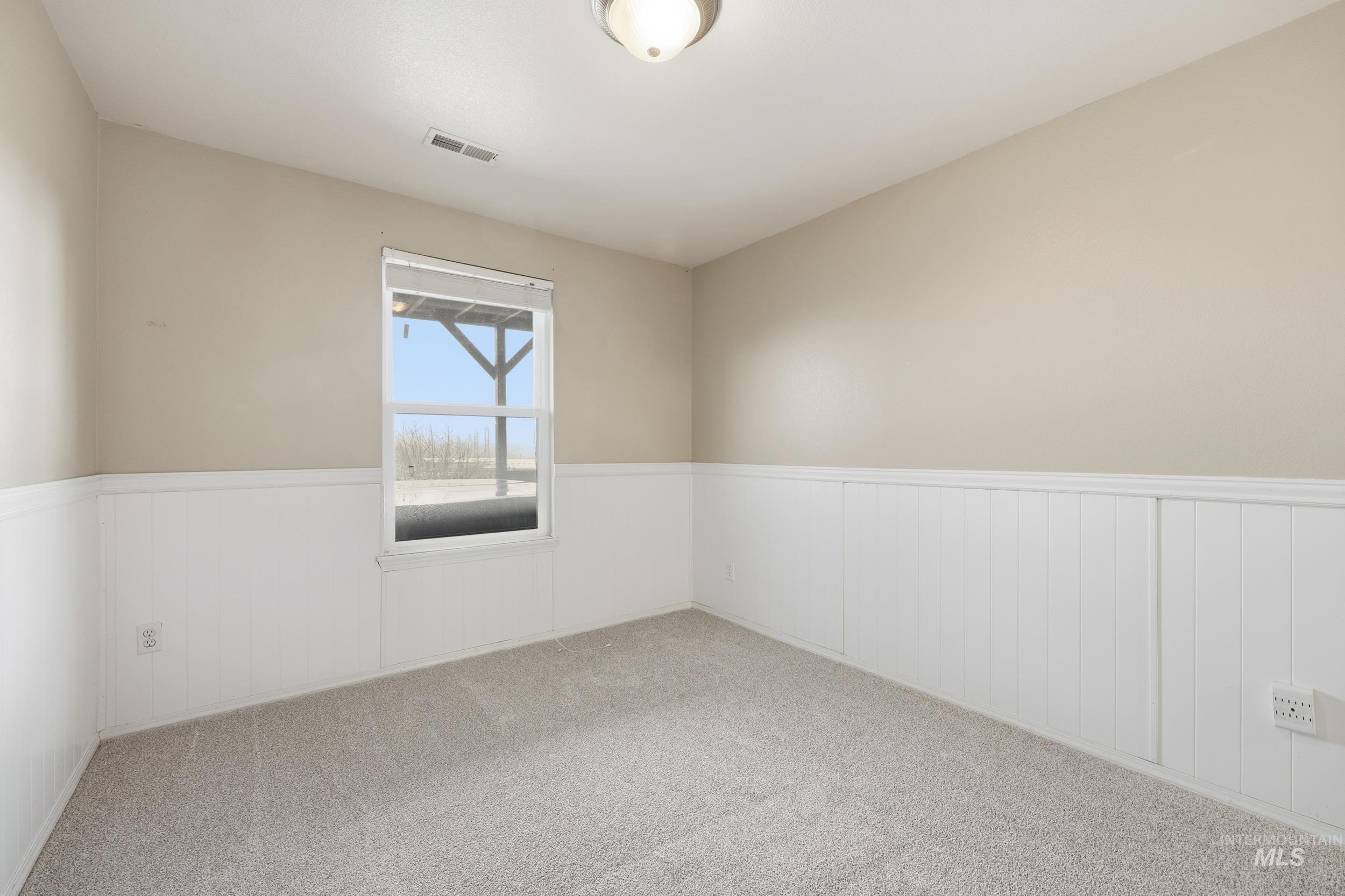 Carpeted empty room with a wainscoted wall