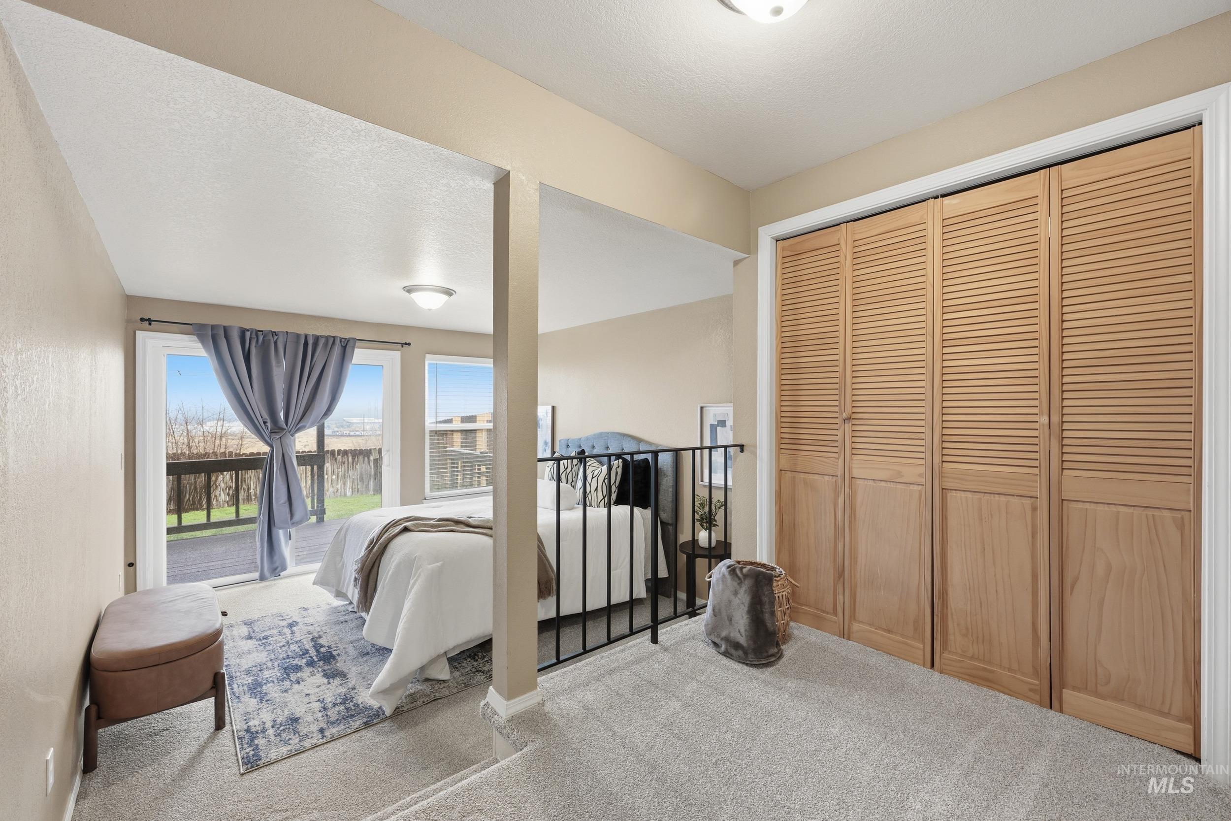 Carpeted bedroom with a closet, a textured ceiling, and access to exterior