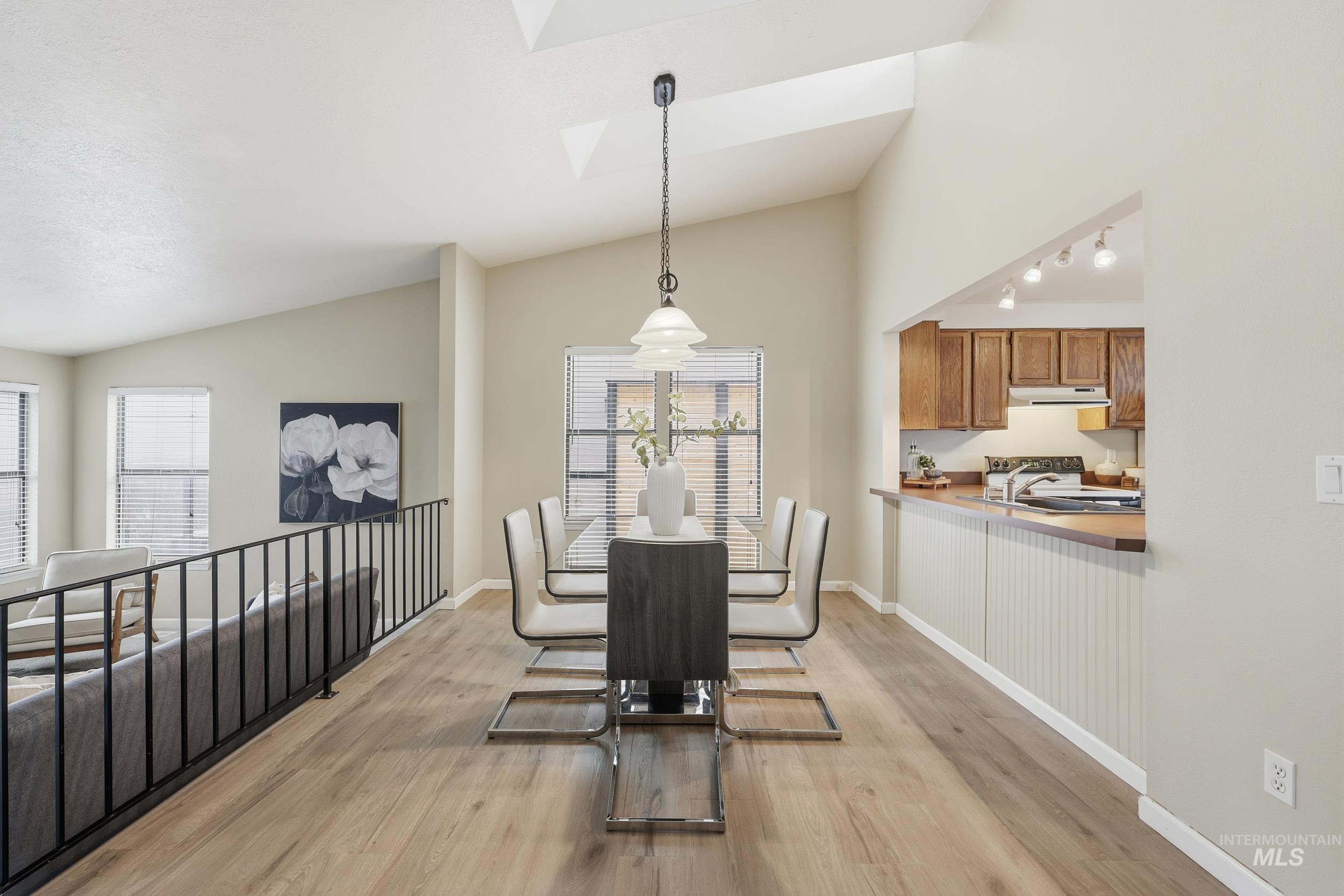 Dining area featuring vaulted ceiling, light wood-style flooring, and a skylight