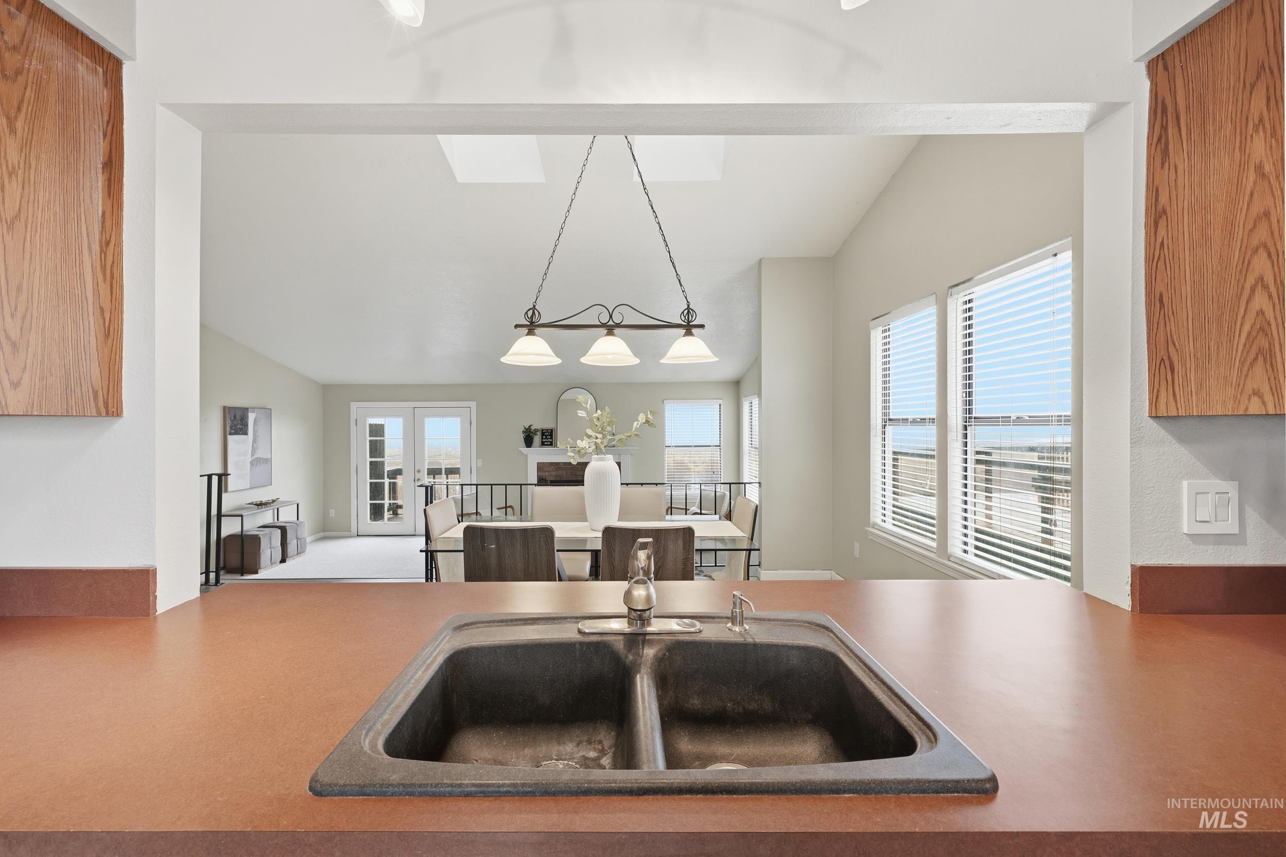 Kitchen featuring lofted ceiling, hanging light fixtures, open floor plan, carpet flooring, and french doors