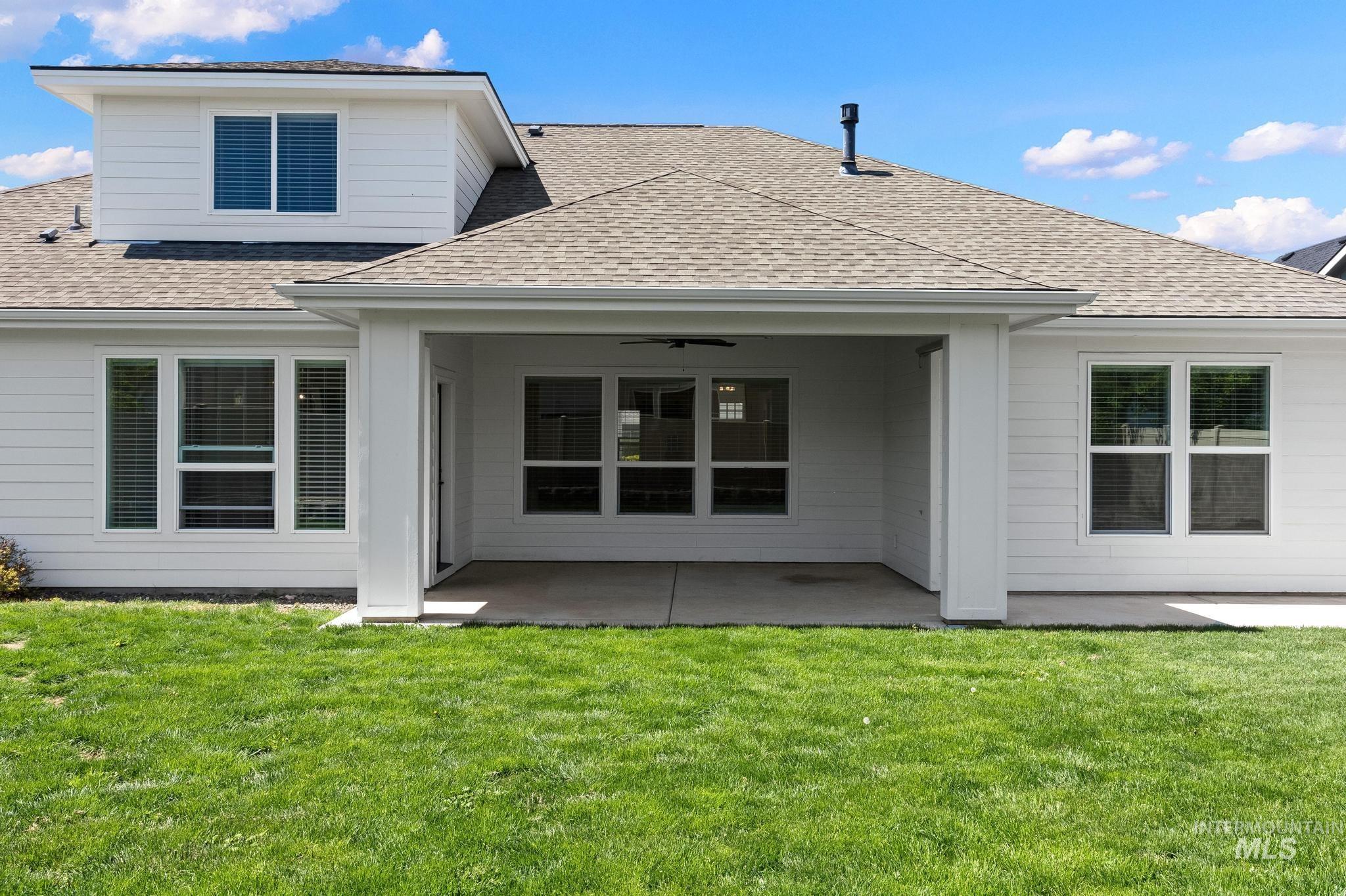 Expansive rear exterior featuring white siding and a covered patio with concrete flooring