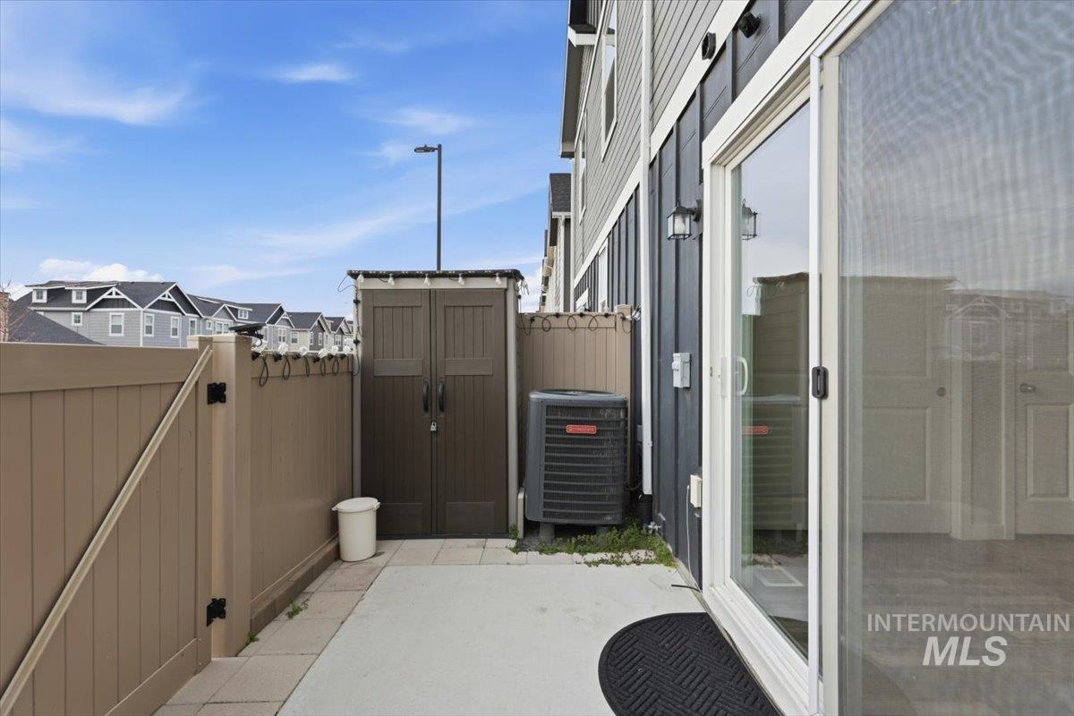 Fenced backyard featuring a storage shed, a patio area, and a gate