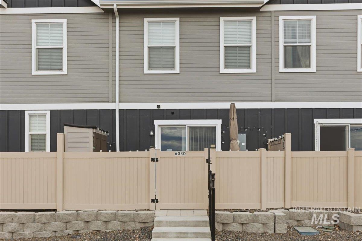 Rear view of property with board and batten siding, a gate, and a fenced front yard