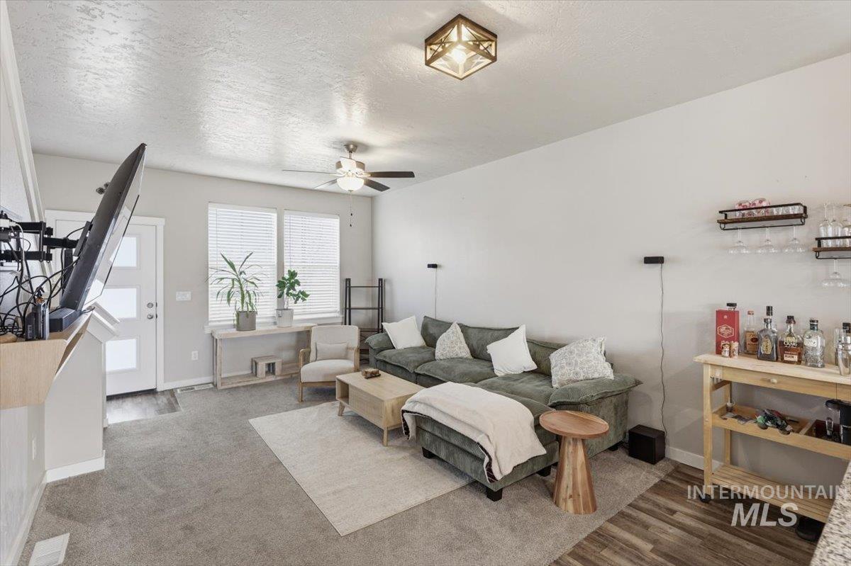 Living area featuring ceiling fan and a textured ceiling