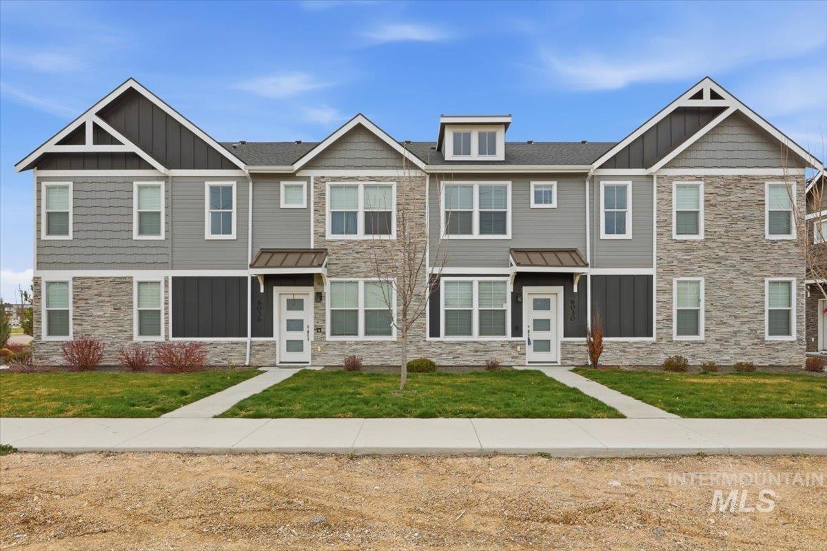 Craftsman-style house with board and batten siding, stone siding, a front yard, and a standing seam roof