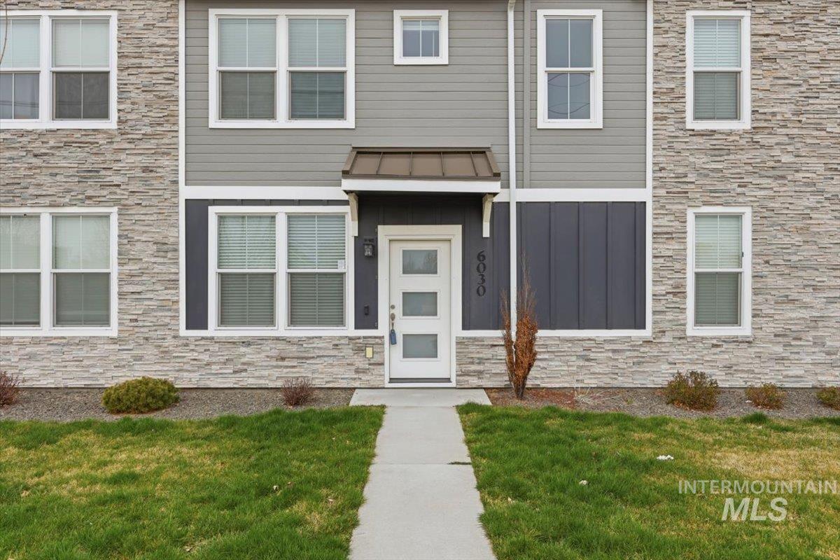 Property entrance with stone siding and a yard