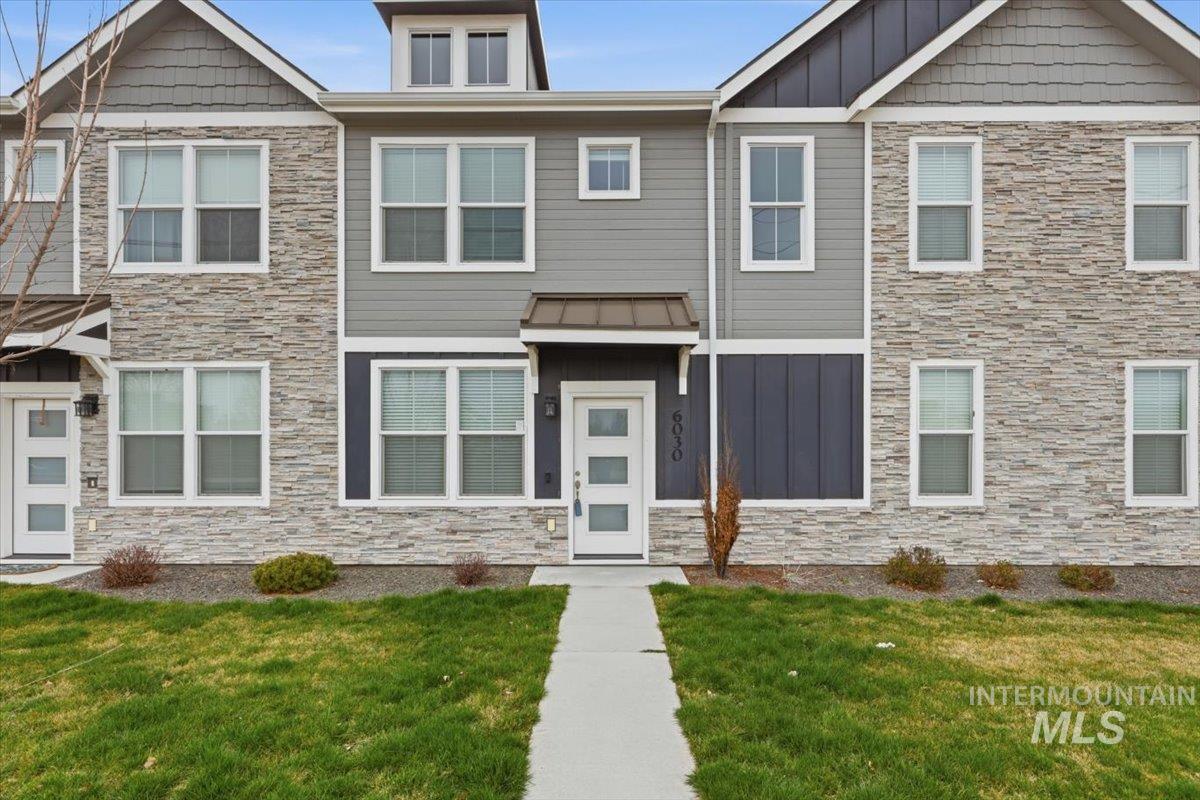 Craftsman-style home with stone siding, board and batten siding, and a front lawn