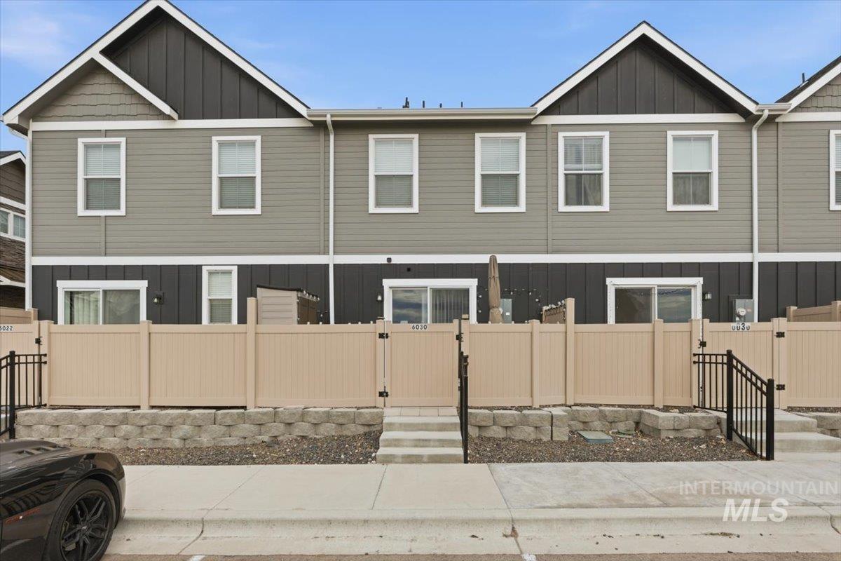 View of front of house with board and batten siding, a gate, and a fenced front yard