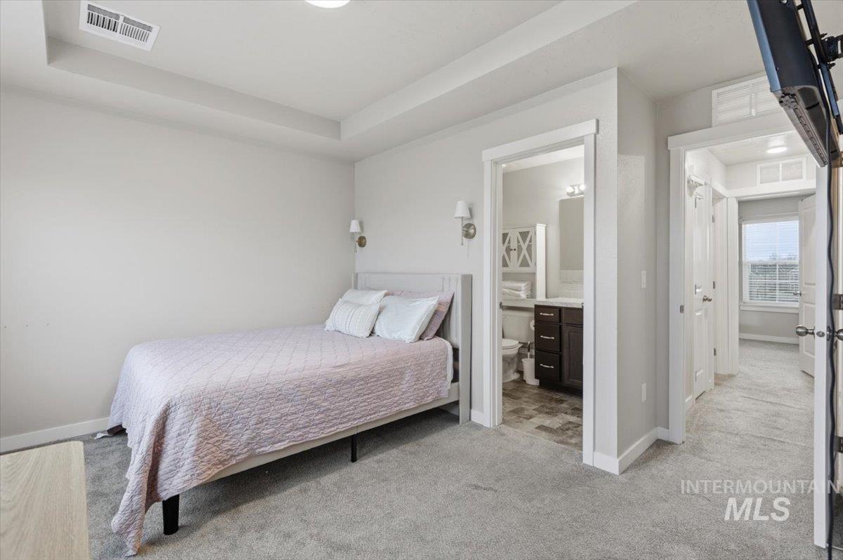 Bedroom with light colored carpet and a raised ceiling