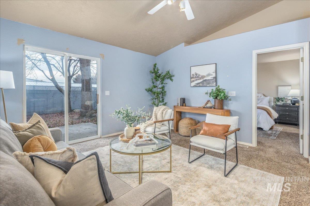 Sitting room with carpet, vaulted ceiling, a ceiling fan, and a textured ceiling
