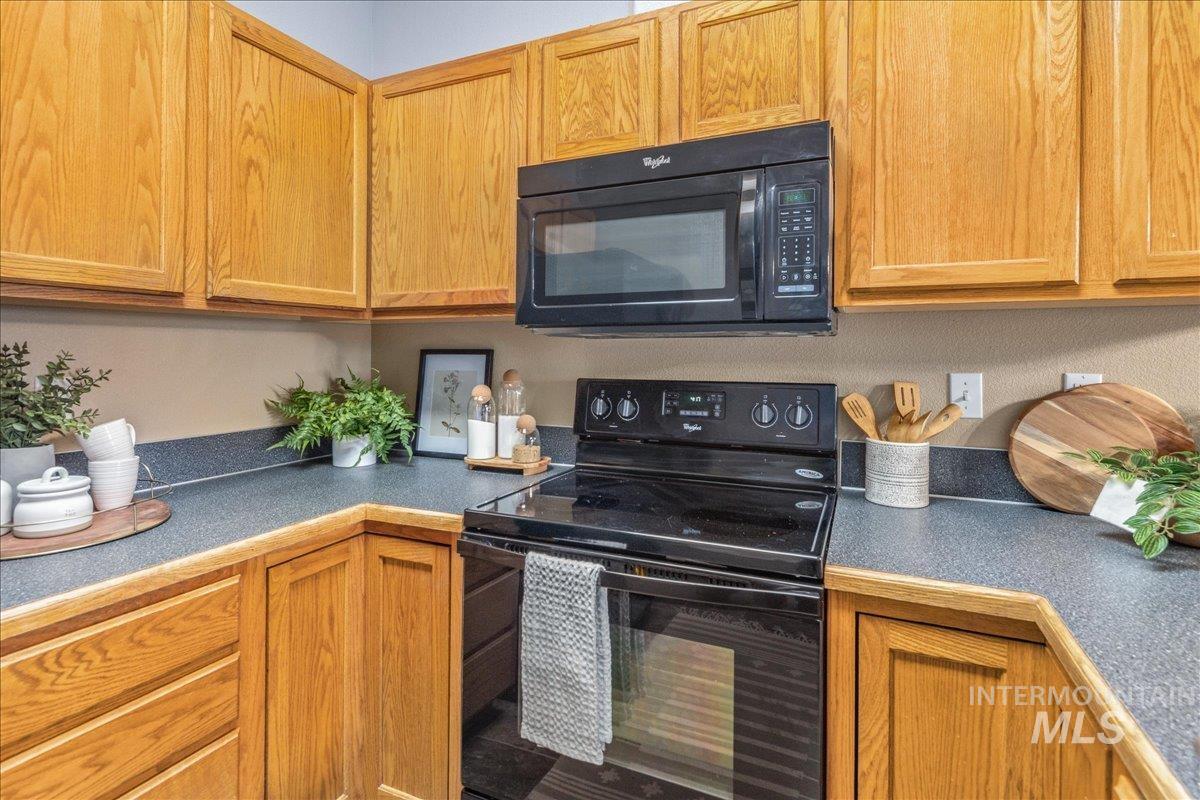 Kitchen with black appliances, dark countertops, and brown cabinetry