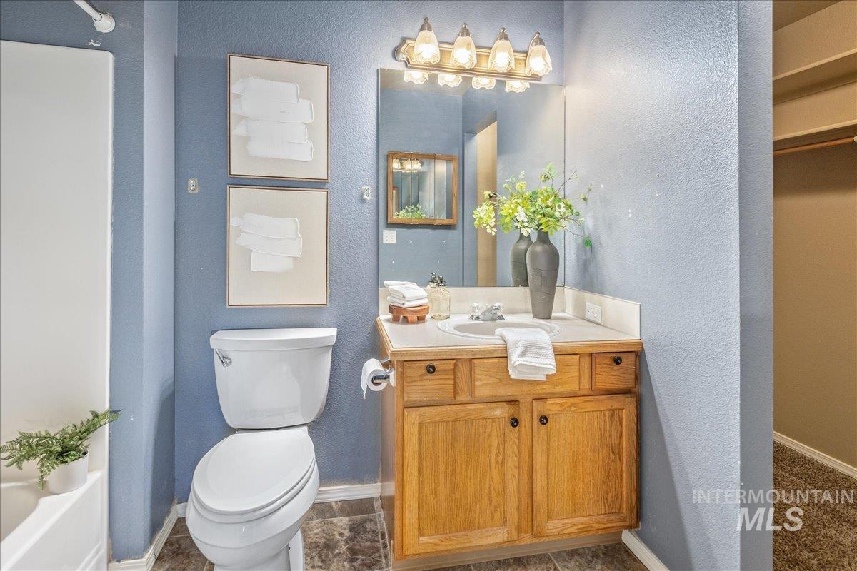 Full bathroom featuring vanity, a textured wall, and a tub to relax in