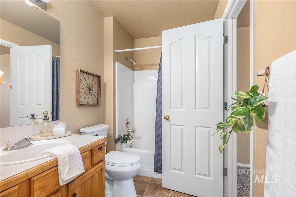 Bathroom with vanity, shower / bath combination with curtain, and light tile patterned floors