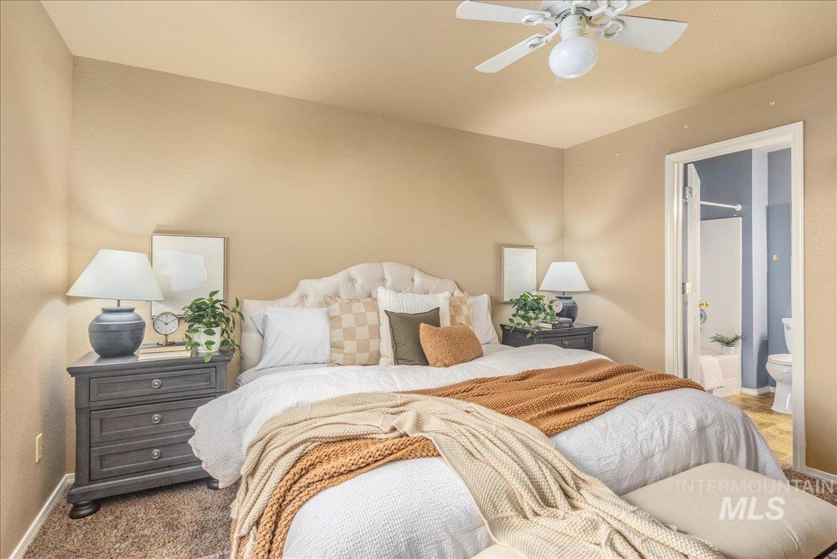 Carpeted bedroom featuring ensuite bath and a ceiling fan