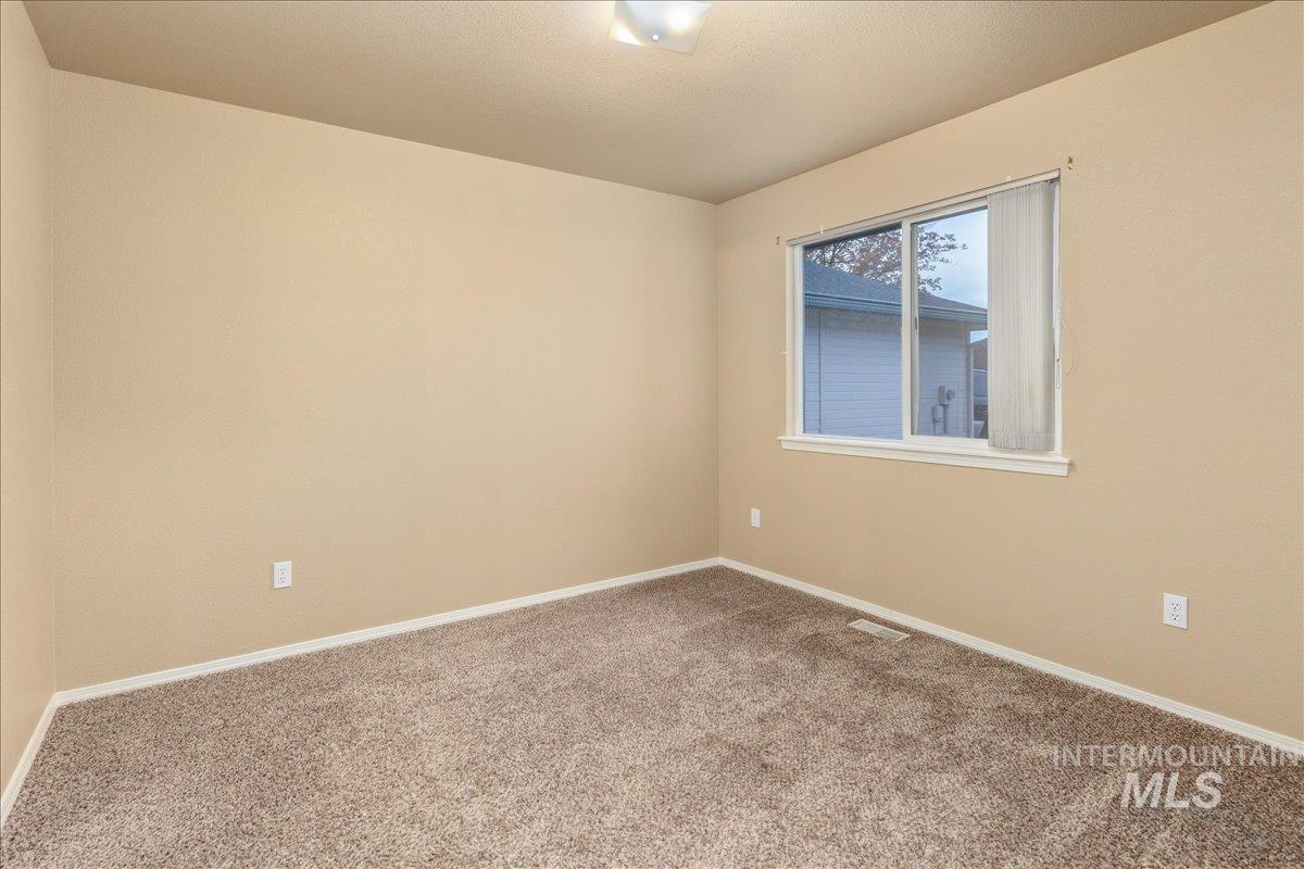Carpeted spare room featuring baseboards