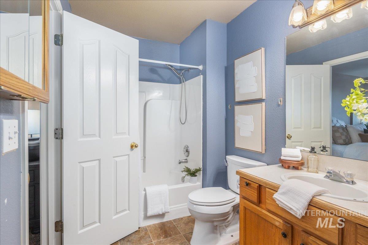 Ensuite bathroom featuring shower / washtub combination, vanity, light tile patterned flooring, and a textured wall