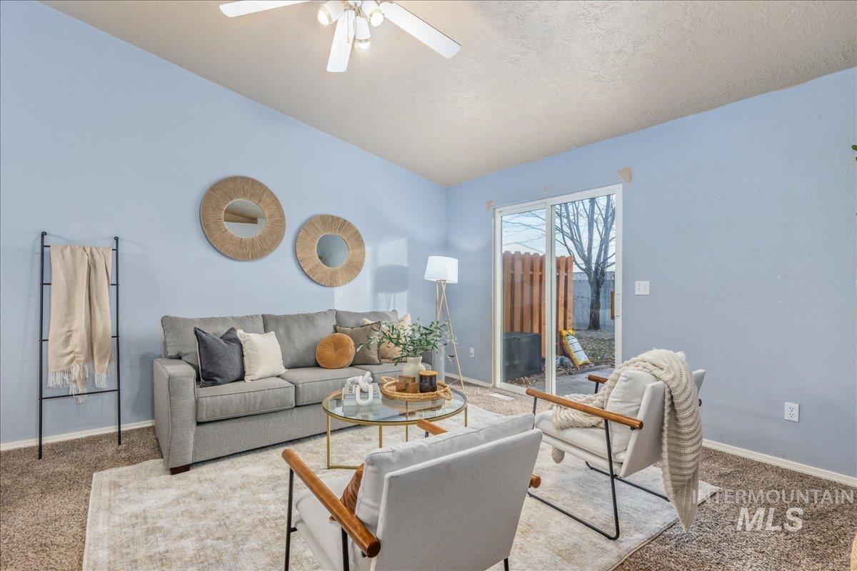 Carpeted living area featuring a textured ceiling, lofted ceiling, and a ceiling fan